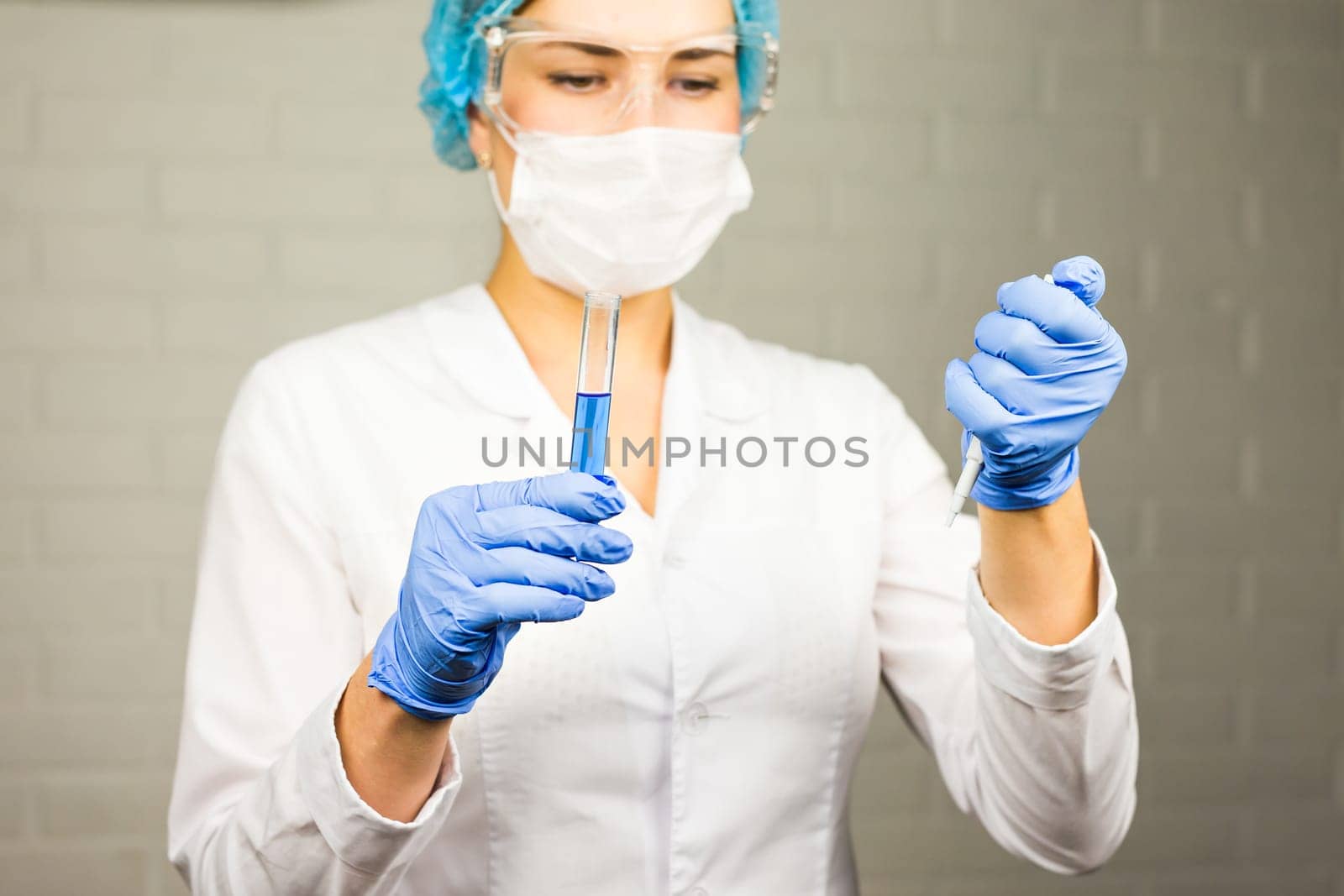 Close-up of glass tube with blue fluid in nurse hand during medical test.