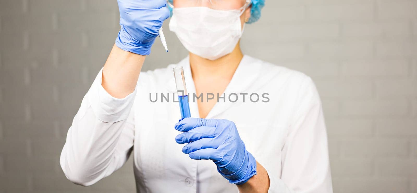 Close-up of glass tube with blue fluid in nurse hand during medical test.