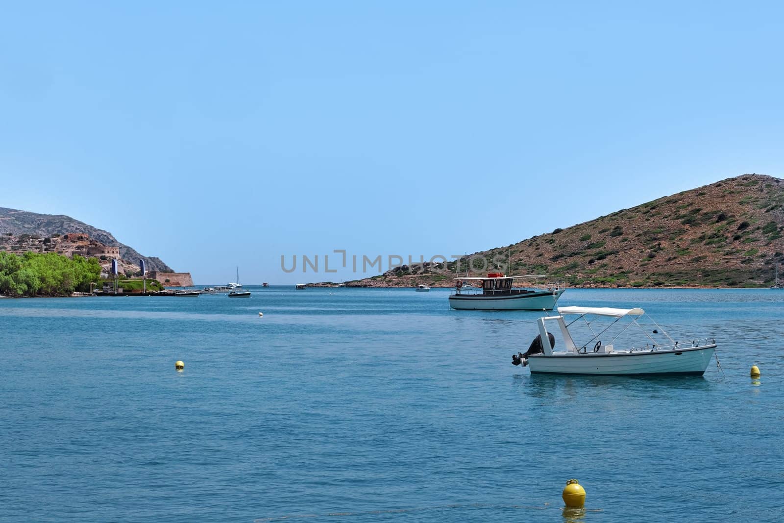 Romantic peaceful view of anchored fishermen's boats on a lagoon and against a hill on a sunny summer day. Crete island, Greece.