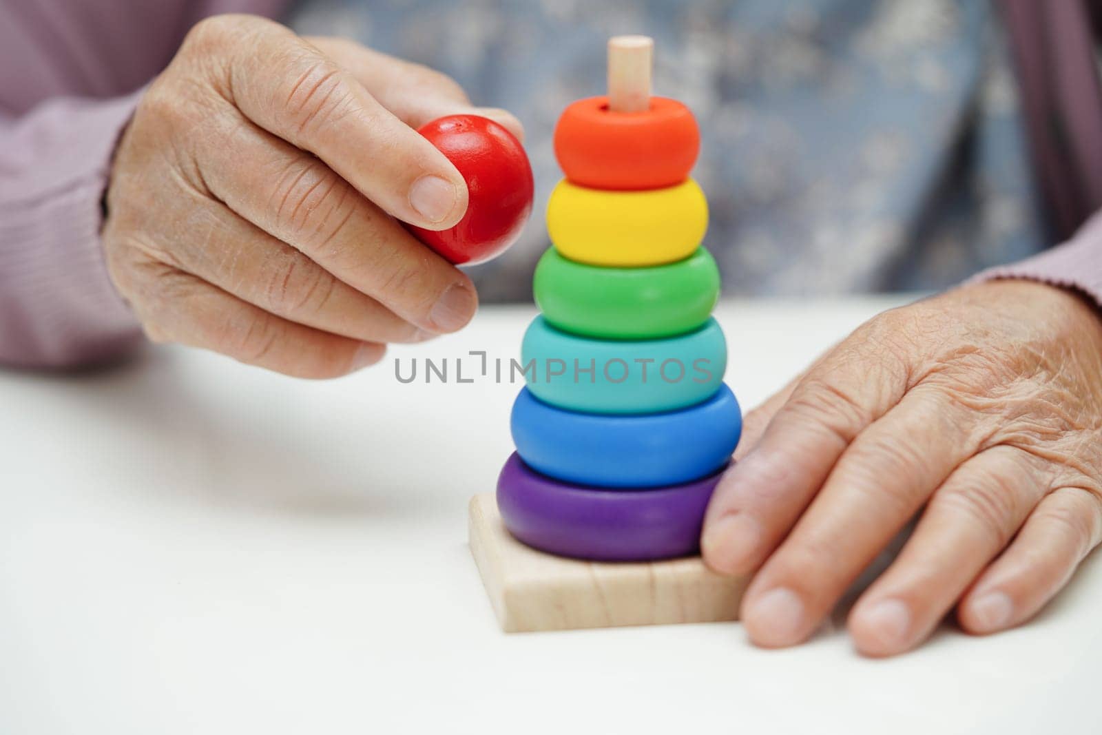 Asian elderly woman playing puzzles game to practice brain training for dementia prevention, Alzheimer disease.