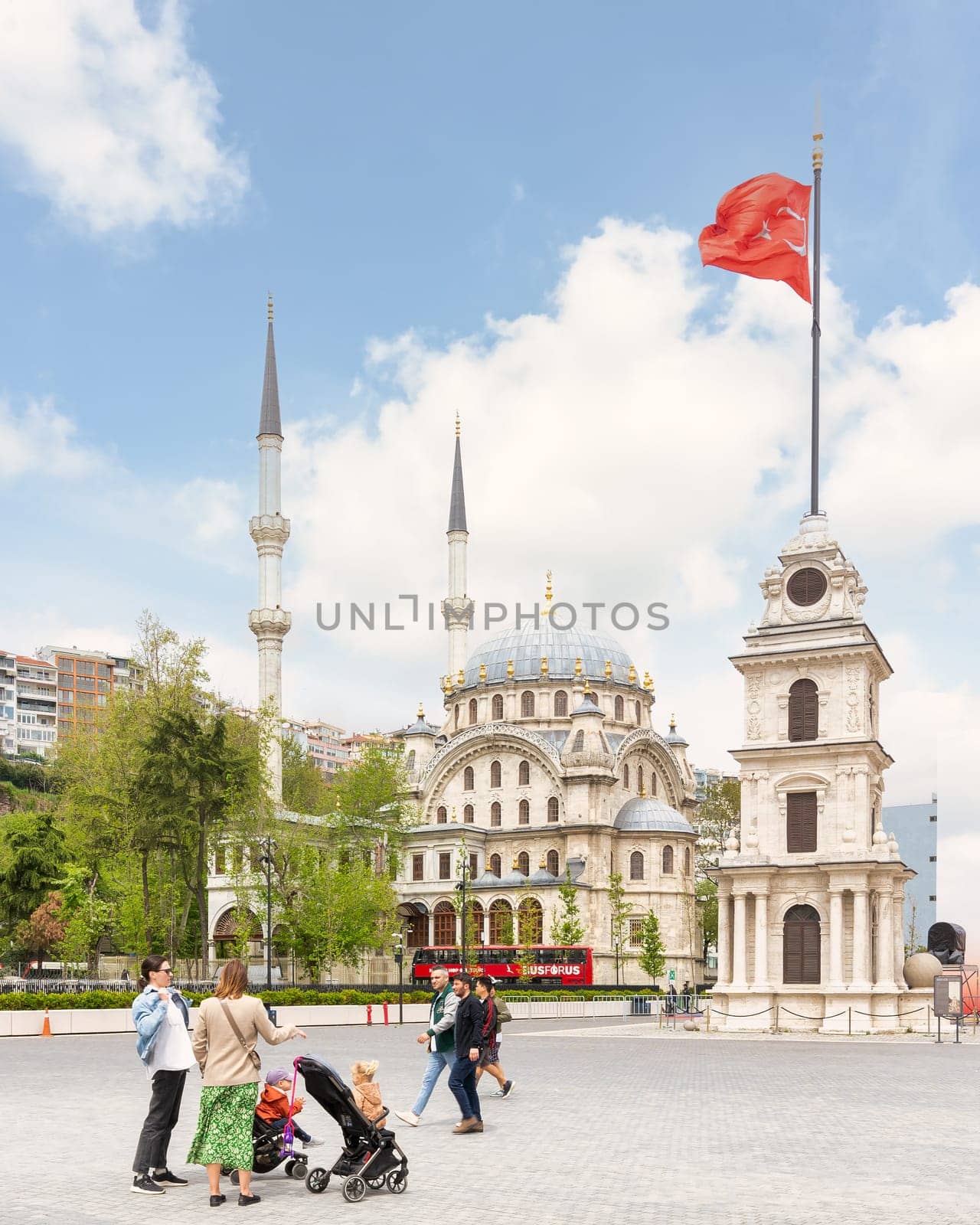 Istanbul, Turkey - May 5 2023: Nusretiye Clock Tower, or Tophane Clock Tower, and Nusretiye imperial Ottoman Mosque, with few pedestrians, Galata Port, Tophane neighborhood, Beyoglu district