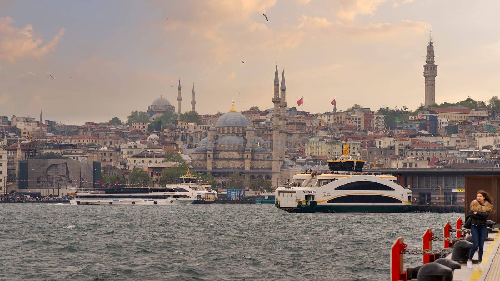 Istanbul, Turkey - May 5, 2023: City view of Istanbul skyline from Galataport overlooking Karakoy ferry terminal with docked ferryboat and Yeni Cami or New Mosque before sunset