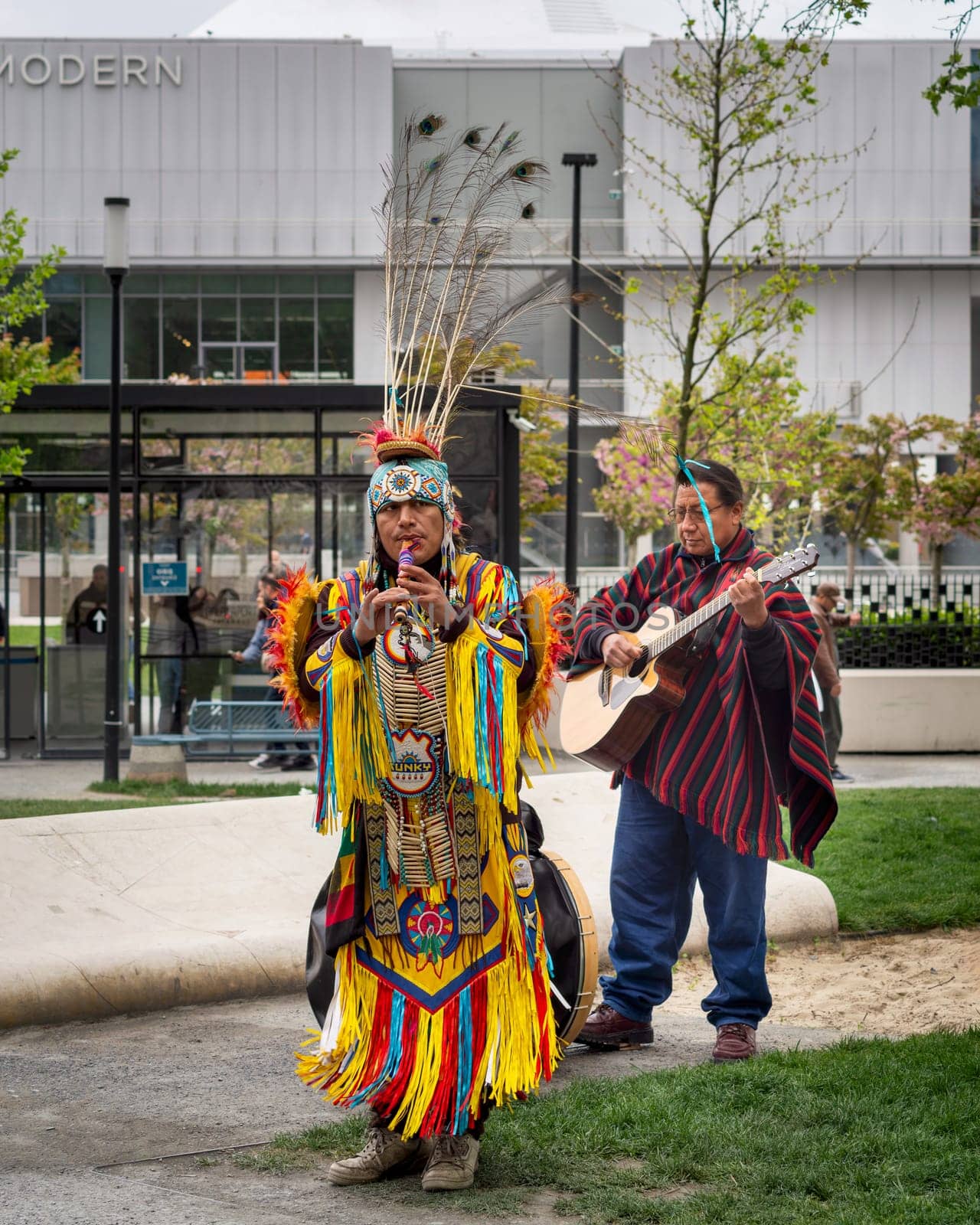 Istanbul, Turkey - May 5, 2023: Two Native Americans musicians wearing colorful traditional costume and busking playing courting flute and guitar in front of Istanbul Modern at Galataport, Karakoy