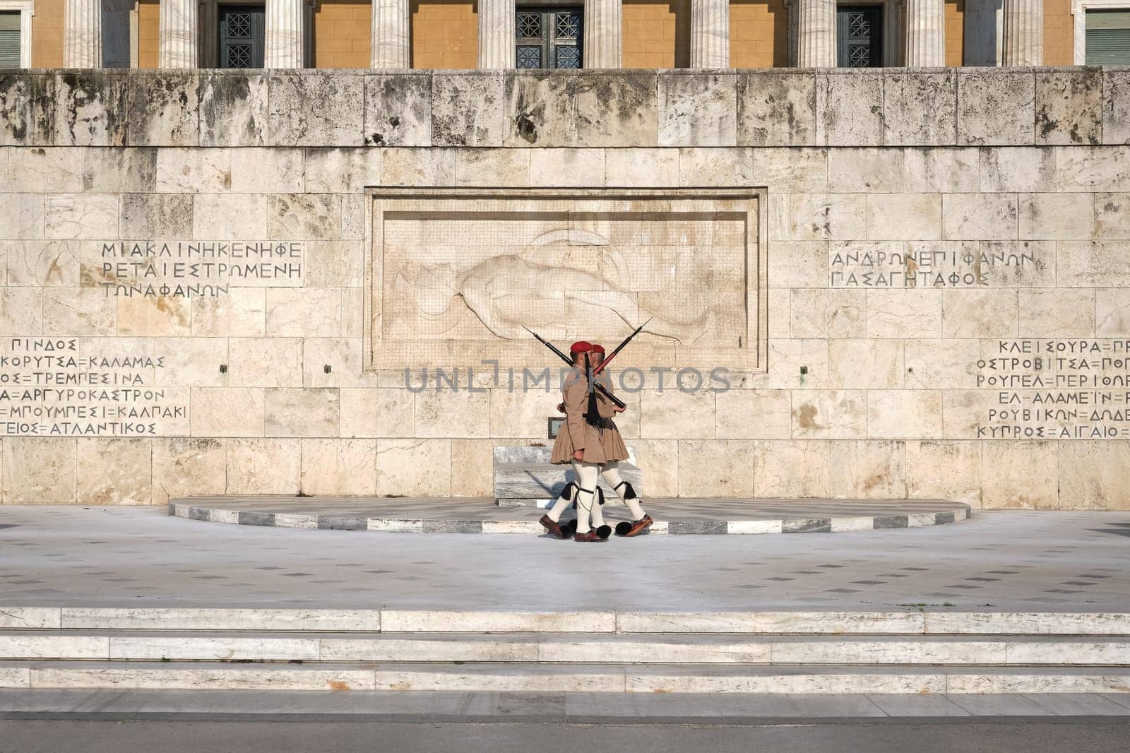 Ceremony of Presidential guard Evzones by the Greek tomb of Unknown Soldier. Evzones in summer uniform, cross by. Wide shot.