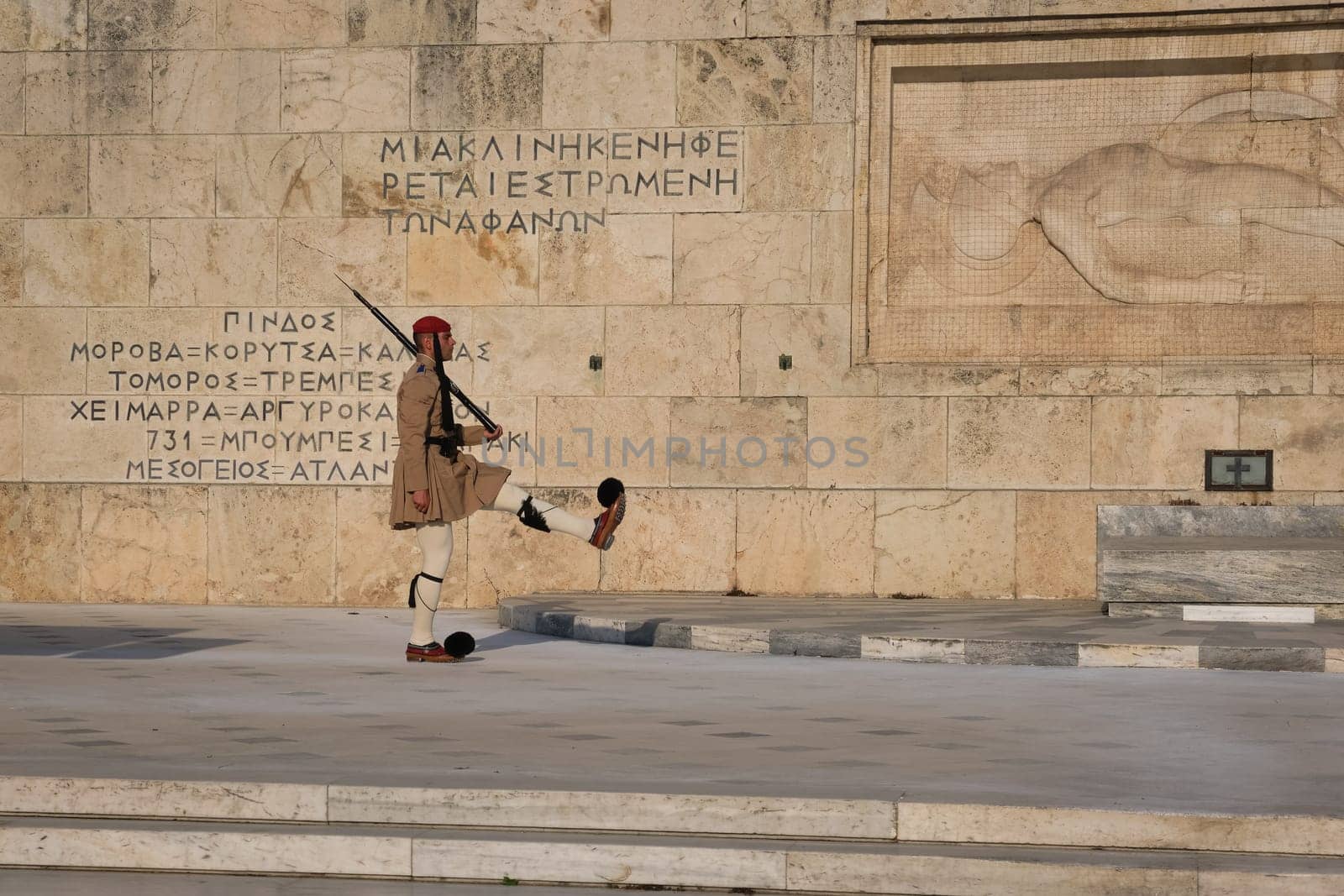 Ceremony of Presidential guard Evzones by the Greek tomb of Unknown Soldier. Evzone in summer uniform marches, leg up. Close shot.