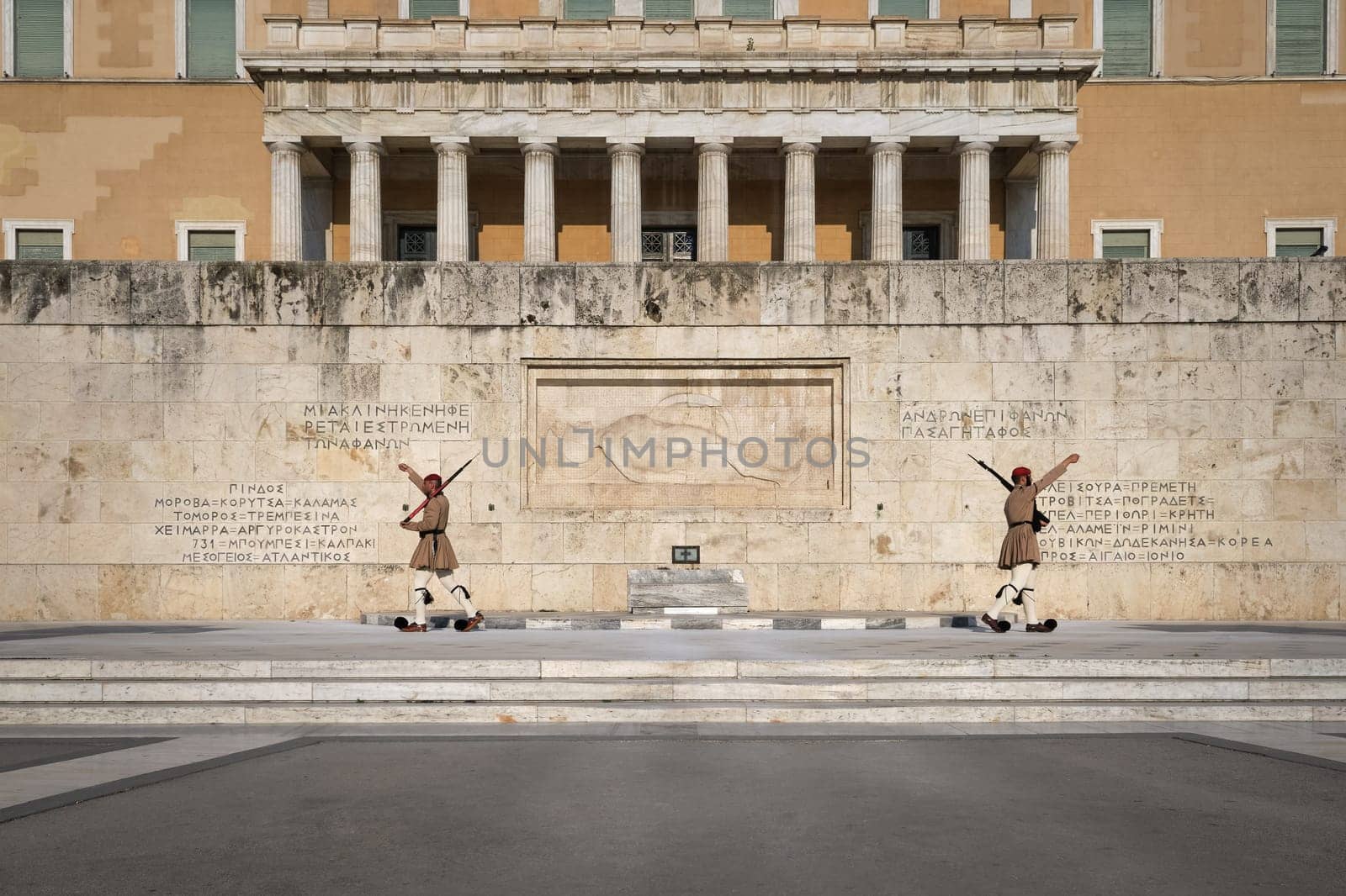 Ceremony of Presidential guard Evzones by the Greek tomb of Unknown Soldier. Evzones in summer uniform separate, hands up. Wide shot.