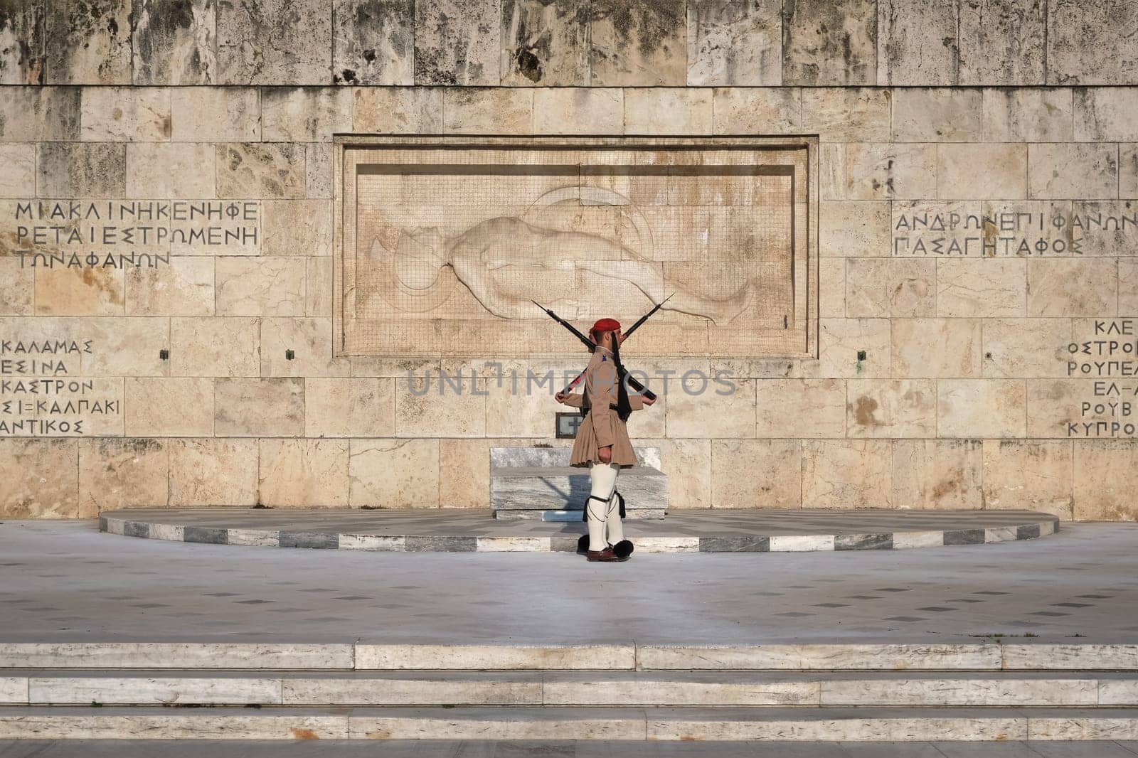 Ceremony of Presidential guard Evzones by the Greek tomb of Unknown Soldier. Evzones in summer uniform stand as one, still. Wide shot.