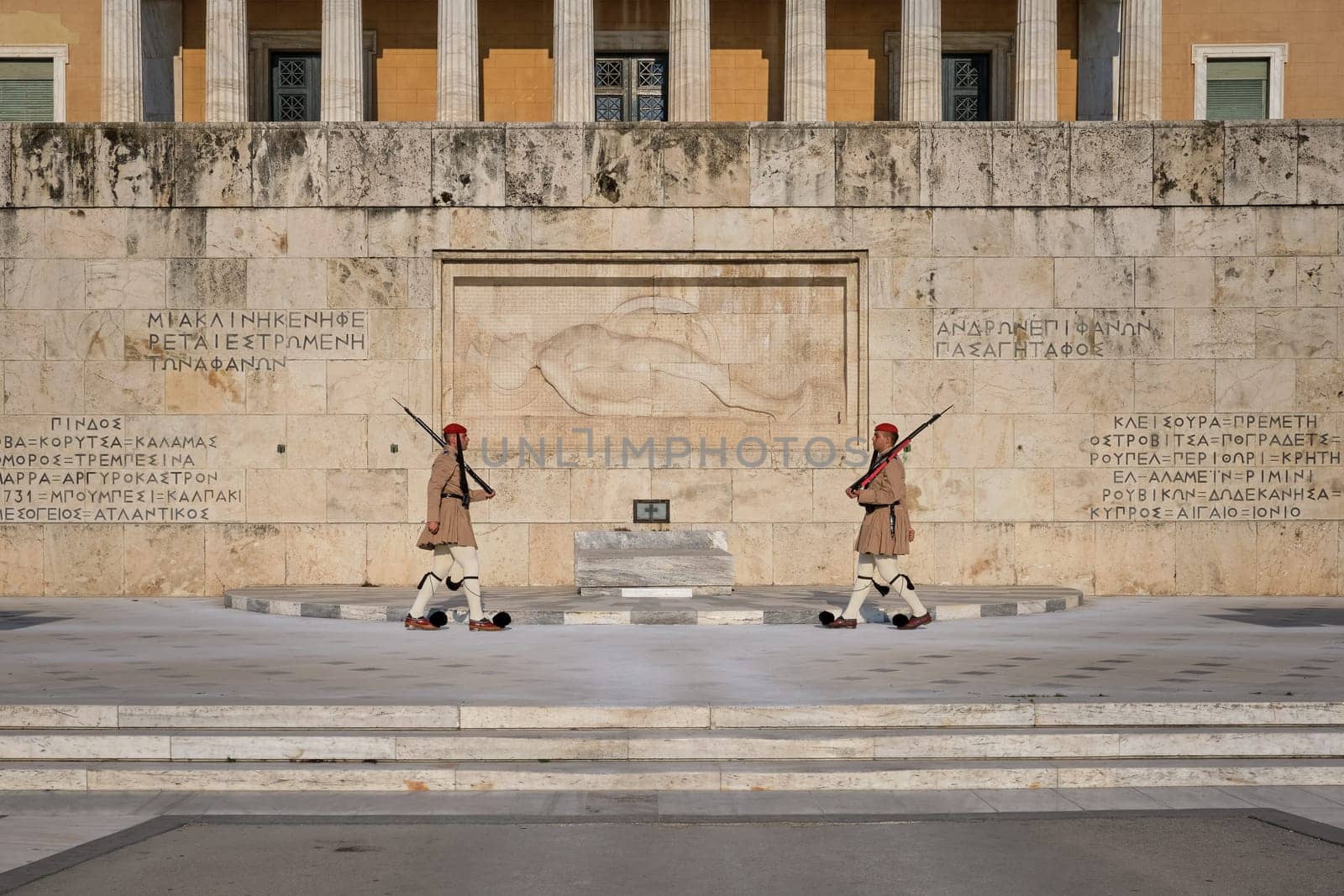 Ceremony of Presidential guard Evzones by the Greek tomb of Unknown Soldier. Evzones in summer uniform walk to each other. Wide shot.