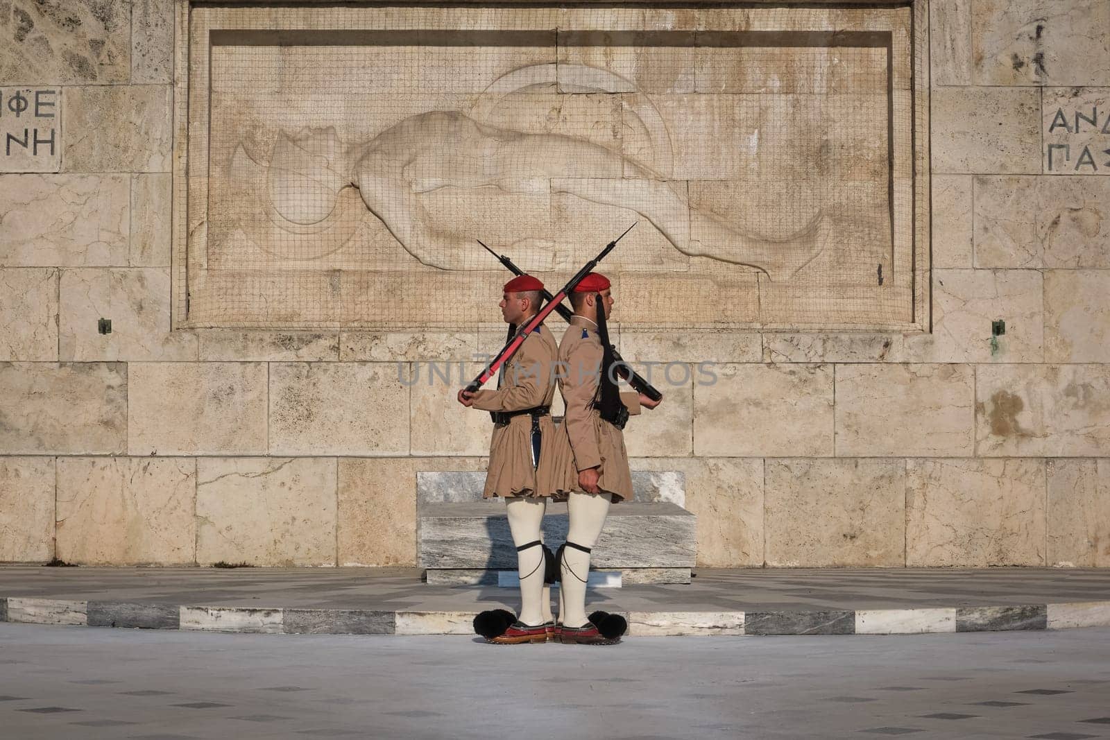 Ceremony of Presidential guard Evzones by the Greek tomb of Unknown Soldier. Evzones in summer uniform stand still and back to back. Close shot.
