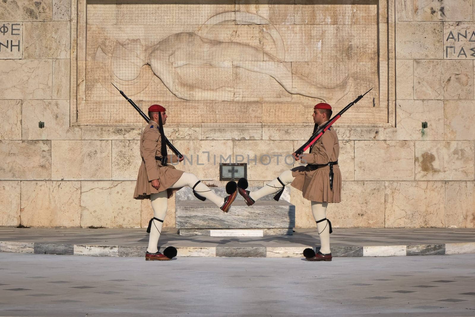 Ceremony of Presidential guard Evzones by the Greek tomb of Unknown Soldier. Evzones in summer uniform face each other, legs up. Close-up shot.