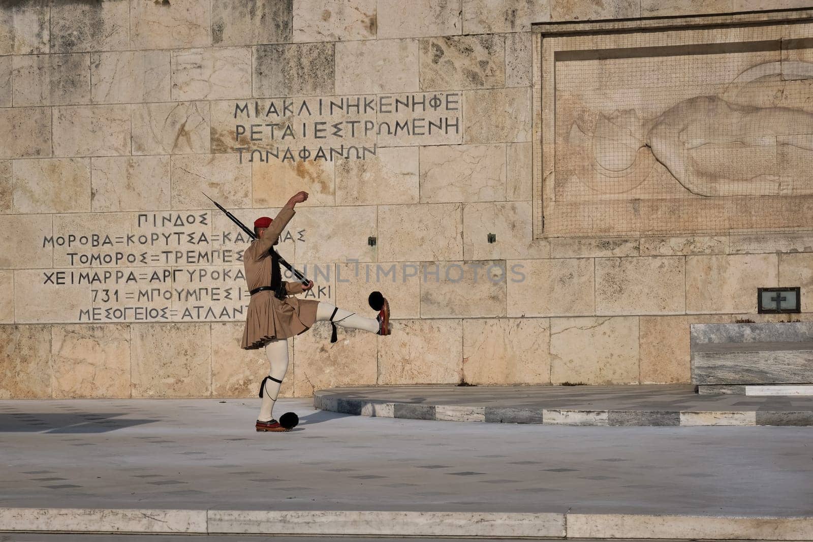 Ceremony of Presidential guard Evzones by the Greek tomb of Unknown Soldier. Evzones in summer uniform marches, leg up, hand up. Close shot.