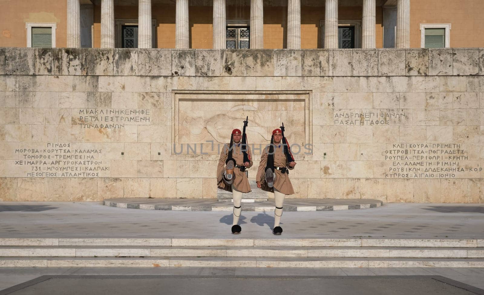 Evzone stand in front of Tomb of Unknown Soldier, legs high up. Wide shot.