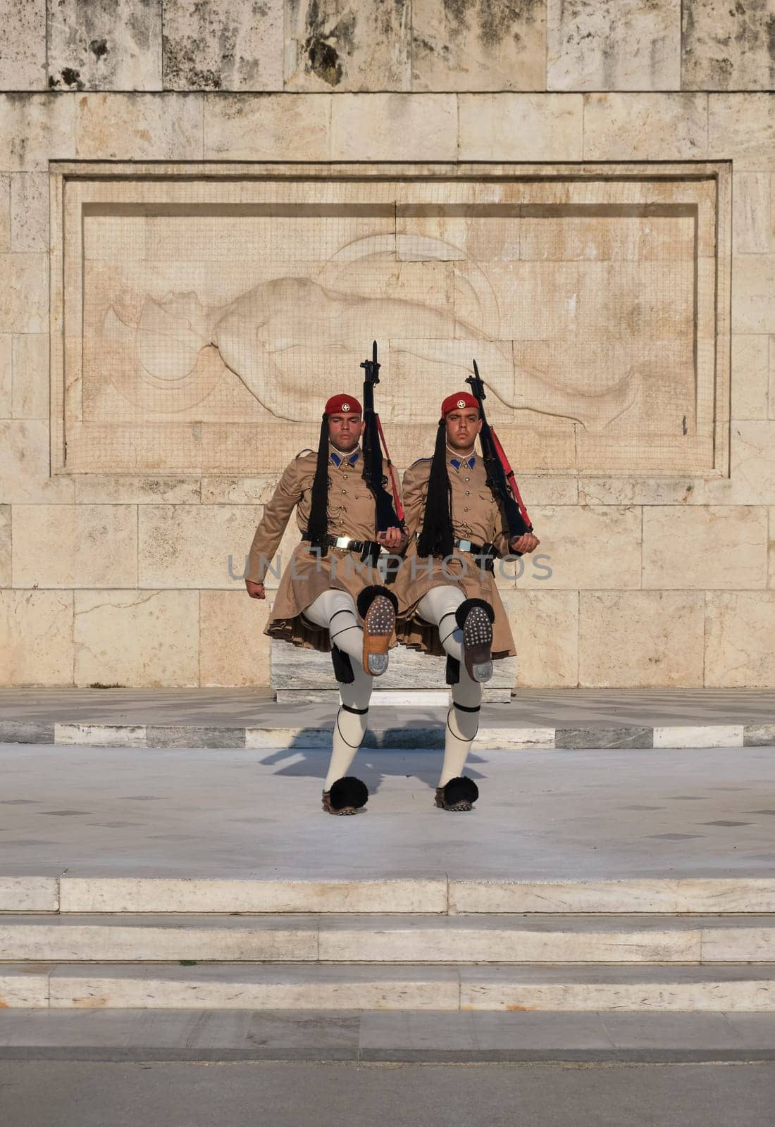 Evzone stand in front of Tomb of Unknown Soldier, legs high up. Close shot.