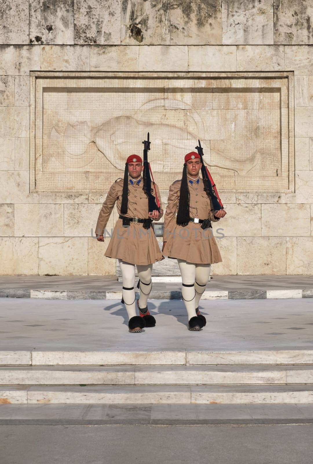 Evzones walk in front of Tomb of Unknown Soldier. Close shot.