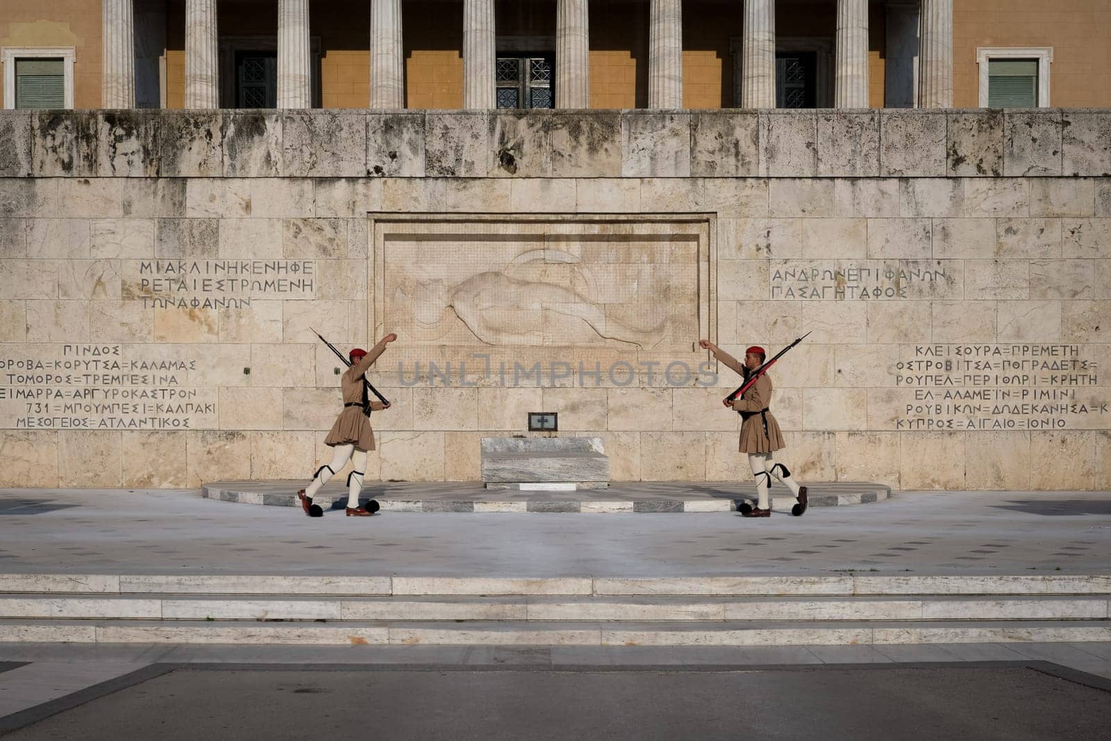 Ceremony of Presidential guard Evzones by the Greek tomb of Unknown Soldier. Evzones in summer uniform face each other, hands up. Wide shot.