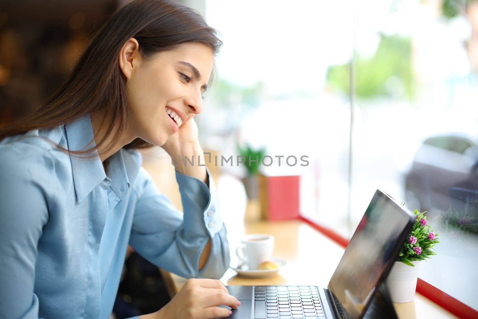 Happy woman in a coffee shop interior using digital tablet