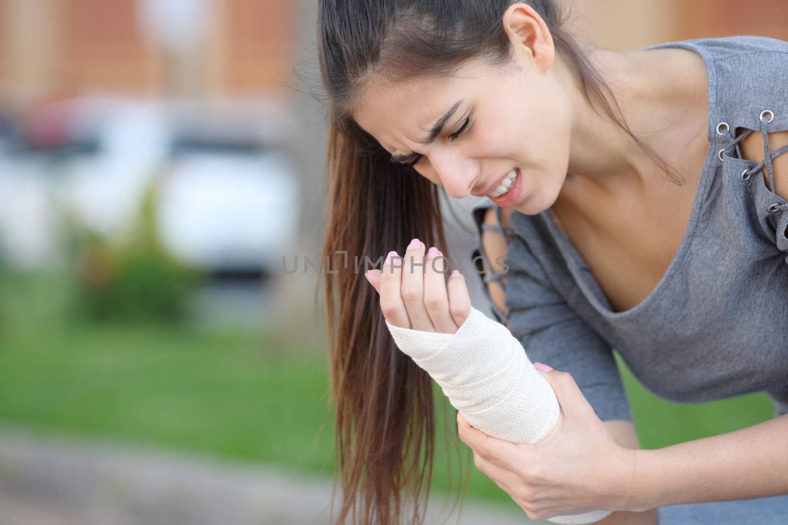 Woman suffering with bandaged sprained wrist in the street