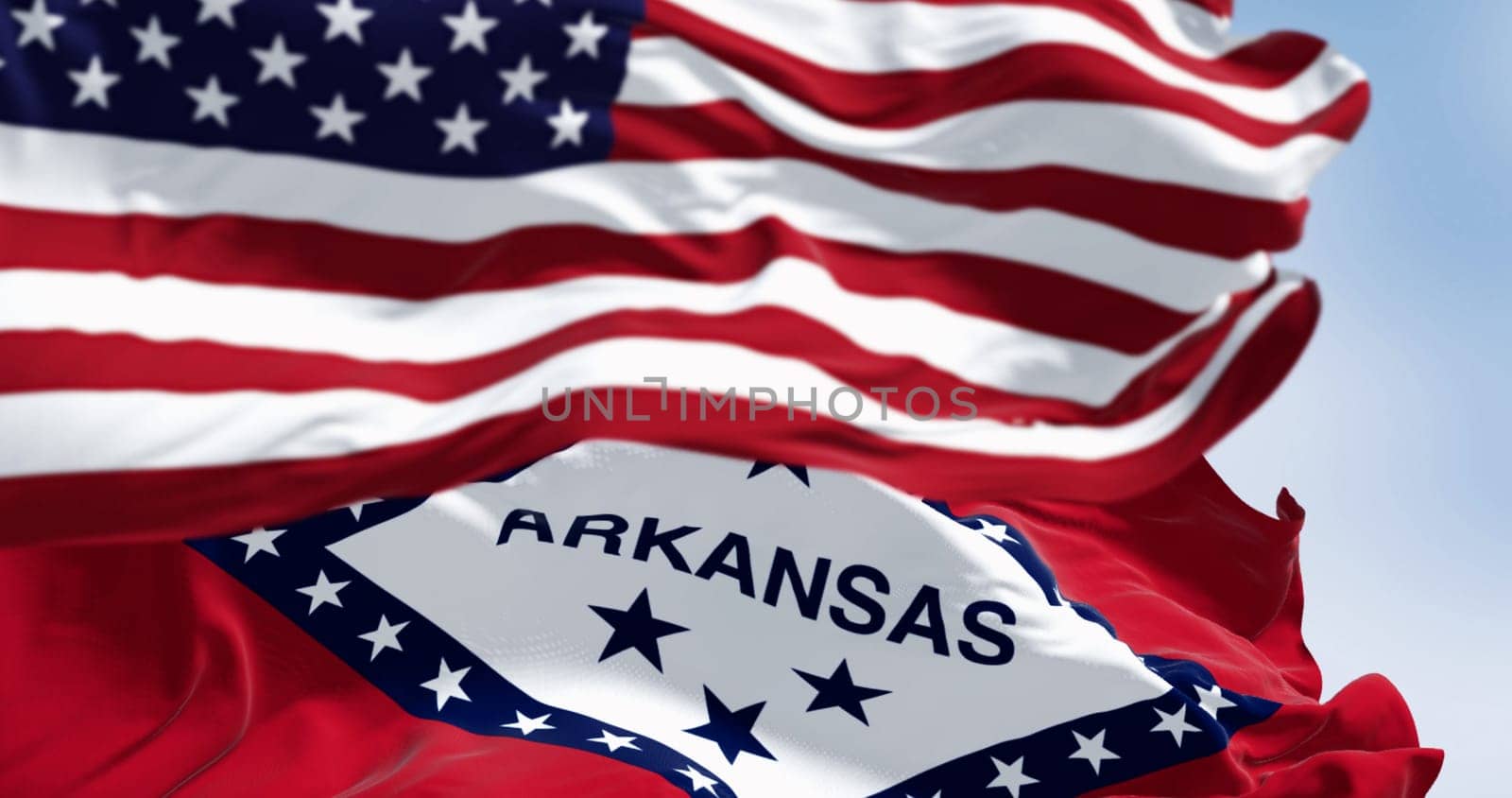 Arkansas state flags waving with the national flag of the United States of America on a clear day. Fluttering fabric. 3d illustration render