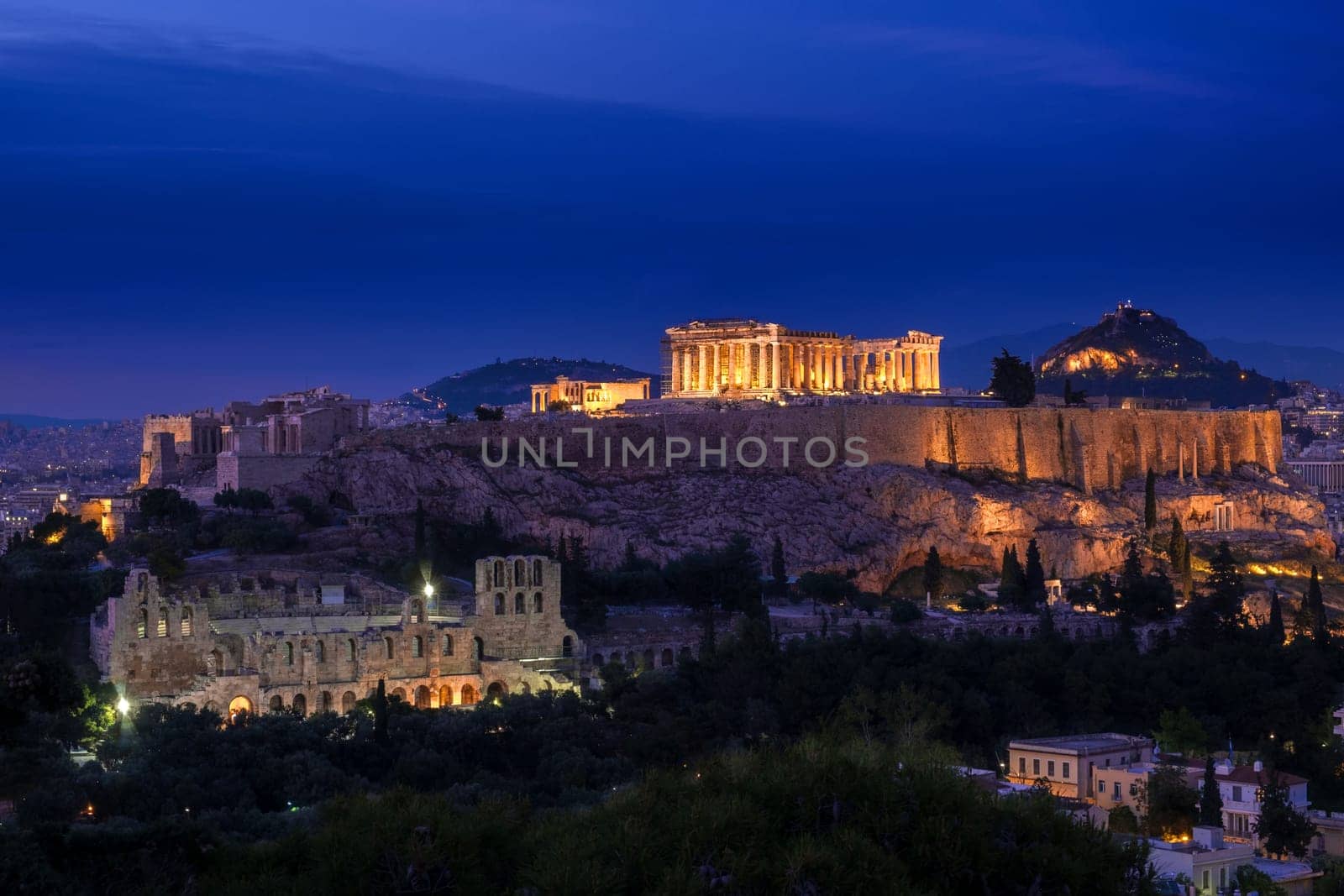Iconic view of Acropolis hill in Athens, Greece at night. Delicate lights of Parthenon and Odeon theater. UNESCO world heritage. Classic architecture, majestic antiquity.