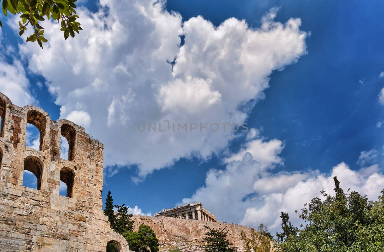 Diagonal dynamic composition of Odeon of Herodes Atticus theater arches on Acropolis hill, Athens, Greece, against bright blue sky and super clouds. Ancient ruins still used as venue for concerts, performances and festivals. UNESCO world heritage.