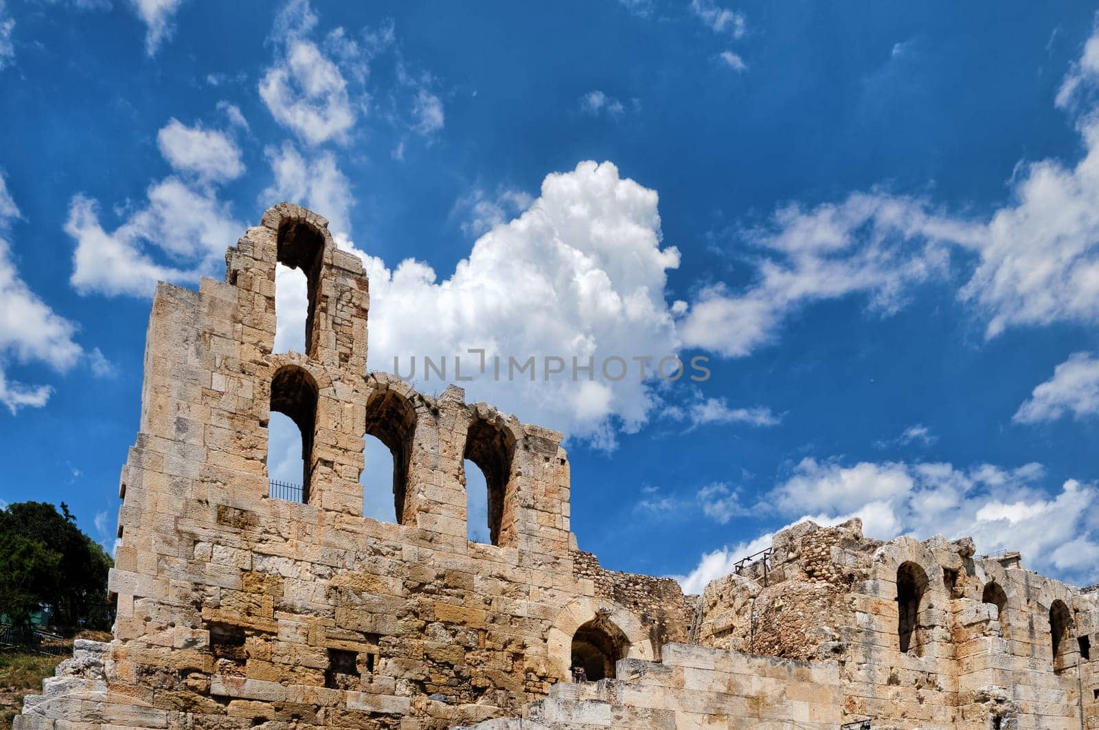 Diagonal dynamic composition of Odeon of Herodes Atticus theater arches on Acropolis hill, Athens, Greece, against bright blue sky and super clouds. Ancient ruins still used as venue for concerts, performances and festivals. UNESCO world heritage.