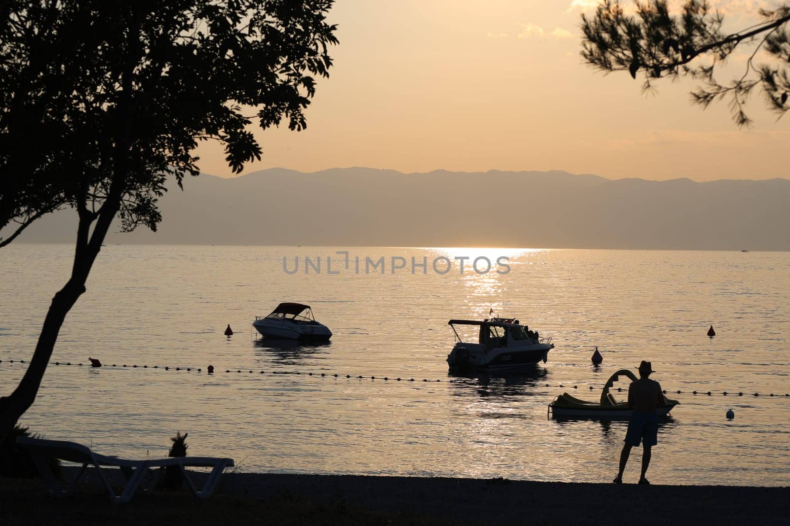 Evening mood on the Adriatic coast off Omisalj/island Krk in Croatia - boats lying near the beach in the water,a man enjoys the atmosphere  Theme picture Croatia / Hrvatska / Croatia 2023