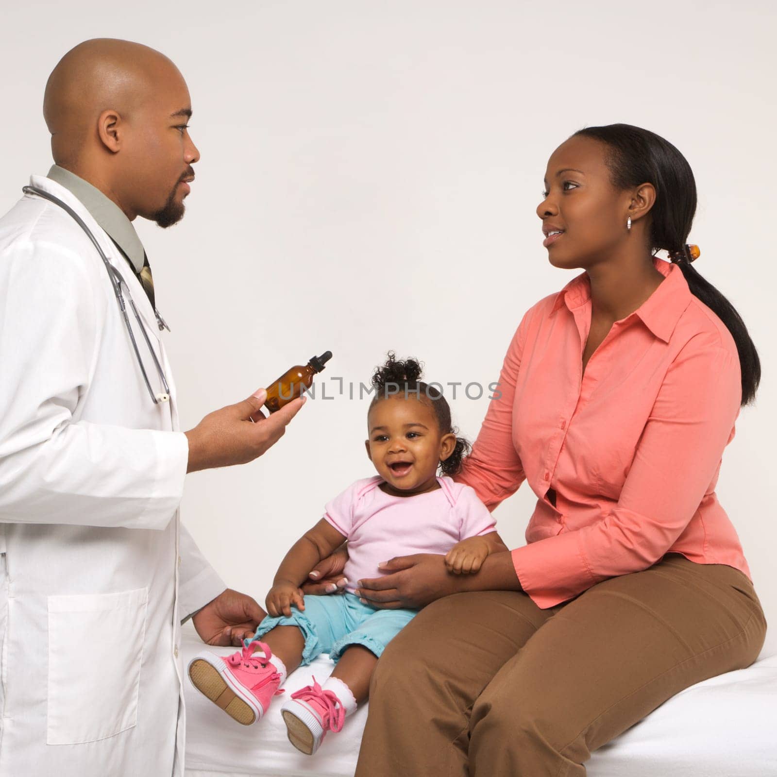 African-American mother and baby girl talking to male pediatrician.