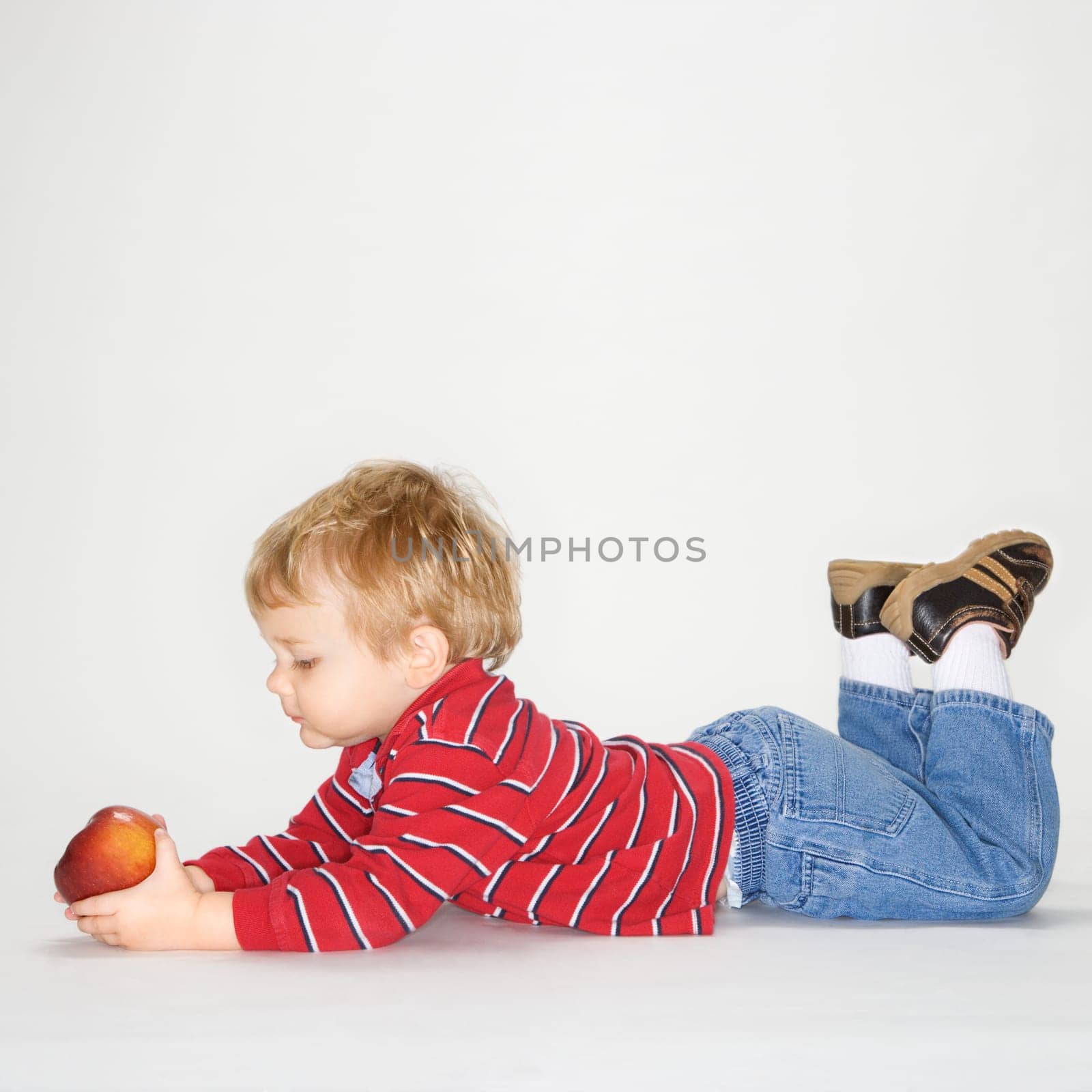 Studio portrait of Caucasian boy holding apple against white background.