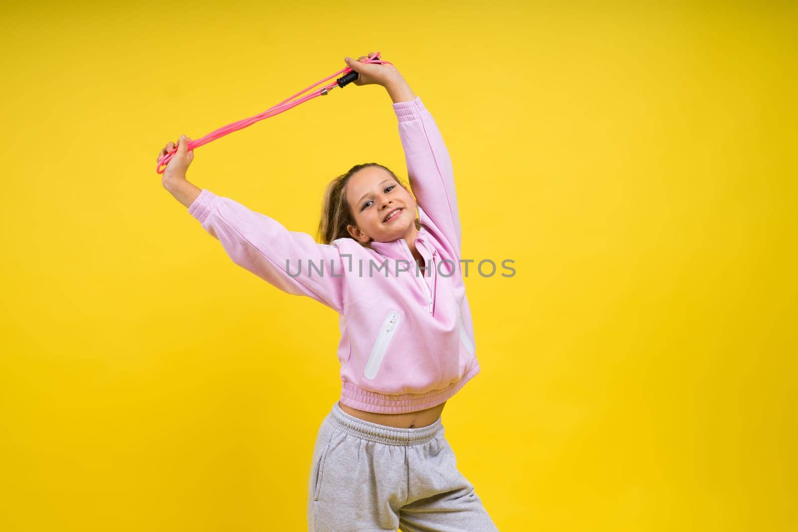 Beautiful sportsgirl with skipping rope isolated on a yellow studio