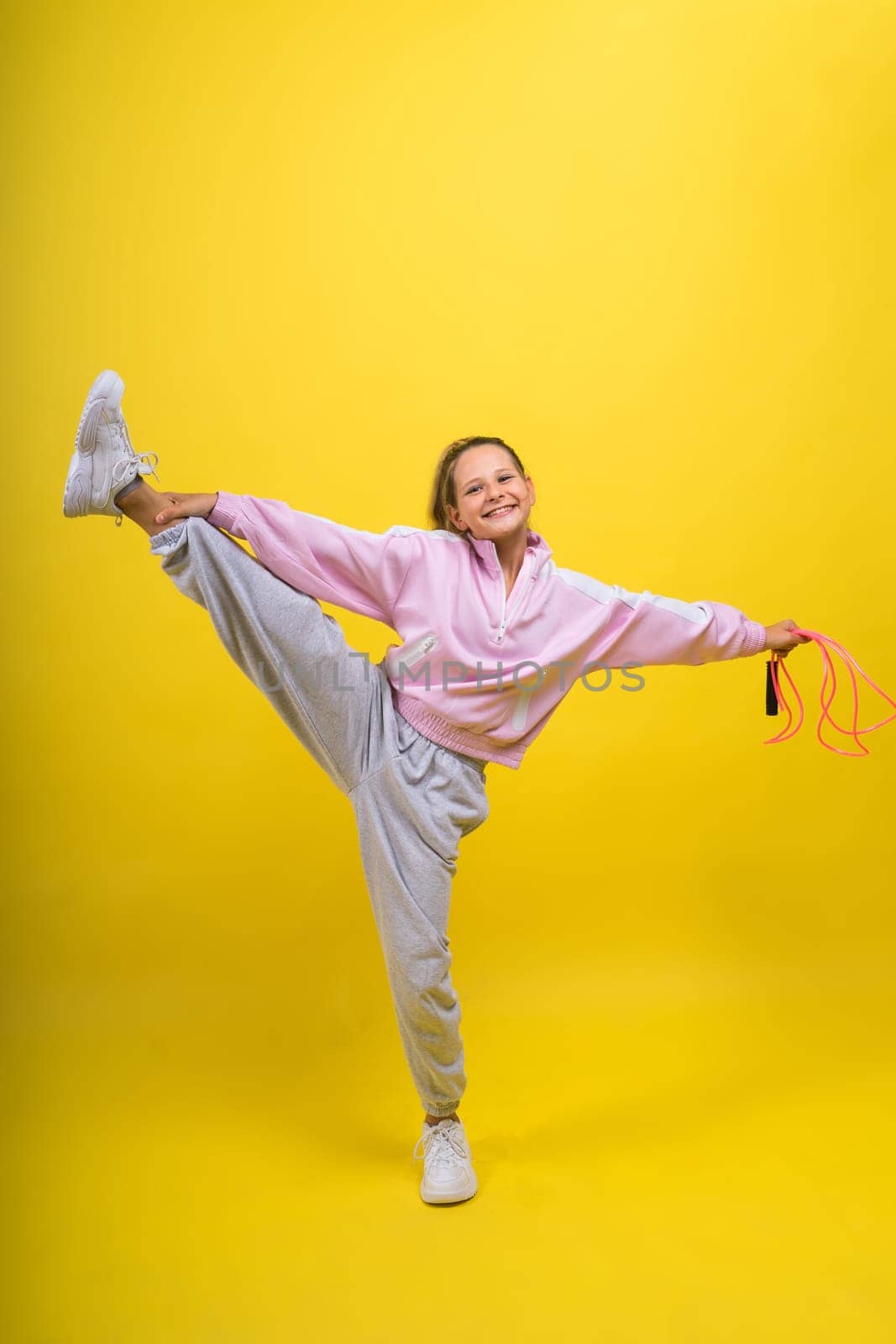 Beautiful sportsgirl with skipping rope isolated on a yellow studio