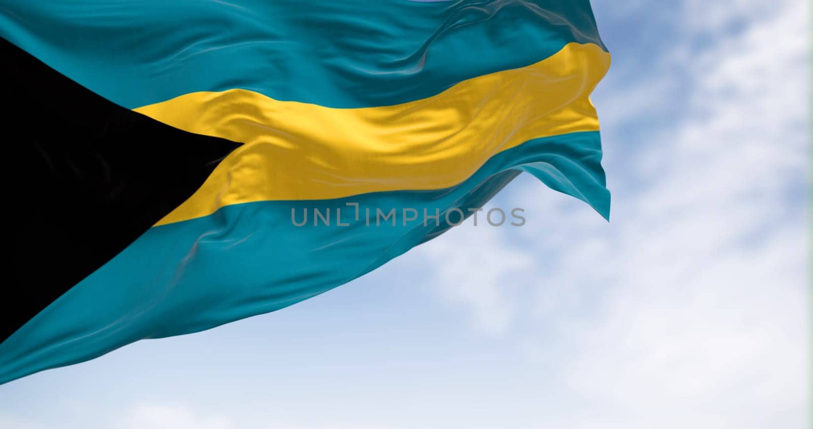 Close-up view of the Bahamas national flag waving in the wind. Black triangle on hoist, aquamarine-gold-aquamarine horizontal bands. 3d render illustration. Rippled fabric.
