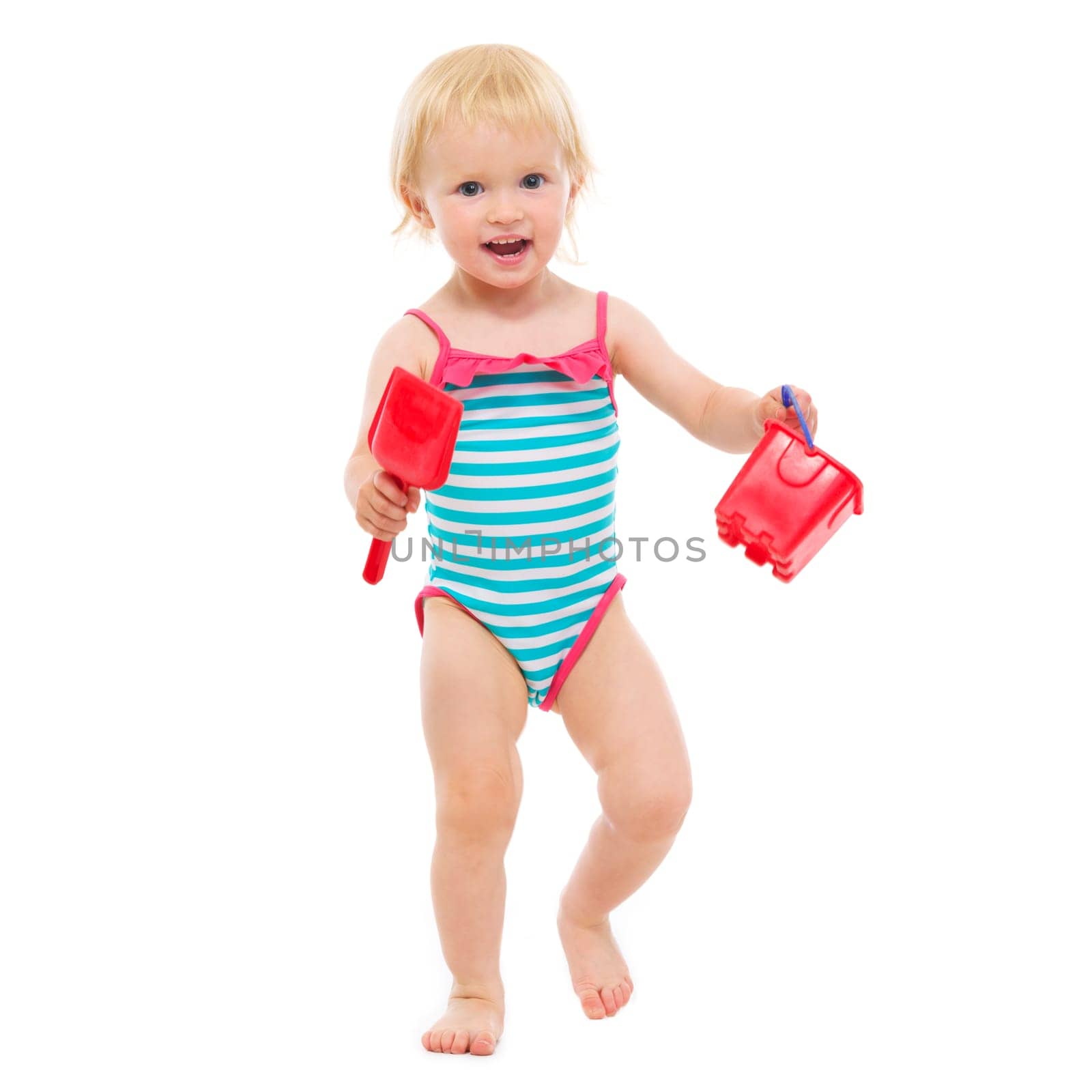 Baby girl in swimsuit holding bucket and shovel