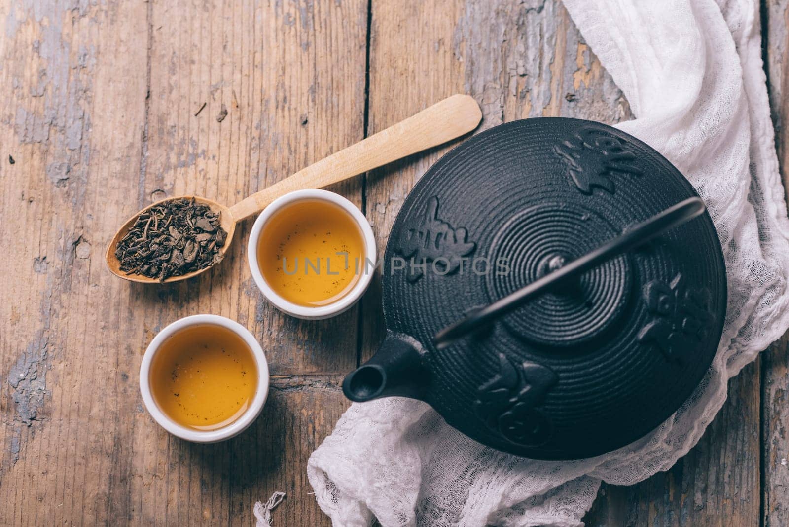 Traditional japanese herbal tea recipe prepared in cast iron teapot with organic dry herbs from above. Top view of asian traditional hot beverage on wooden table.