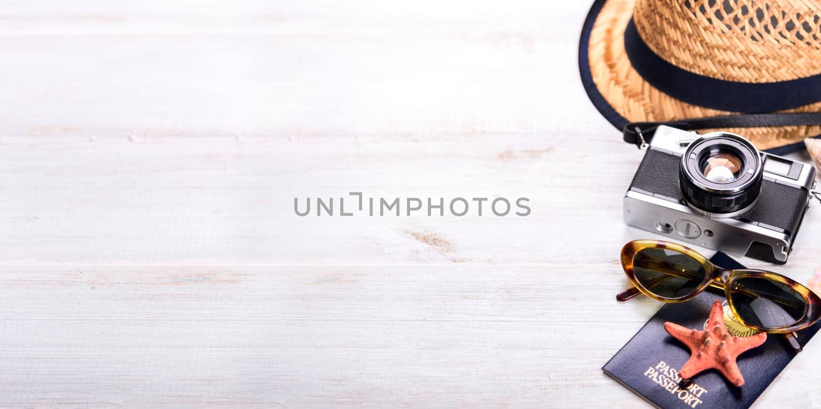 Vintage photo camera, passport, and sunglasses  border on wooden white background from above. Summer holiday vacation design with copyspace top view. Travel and tourism concept.