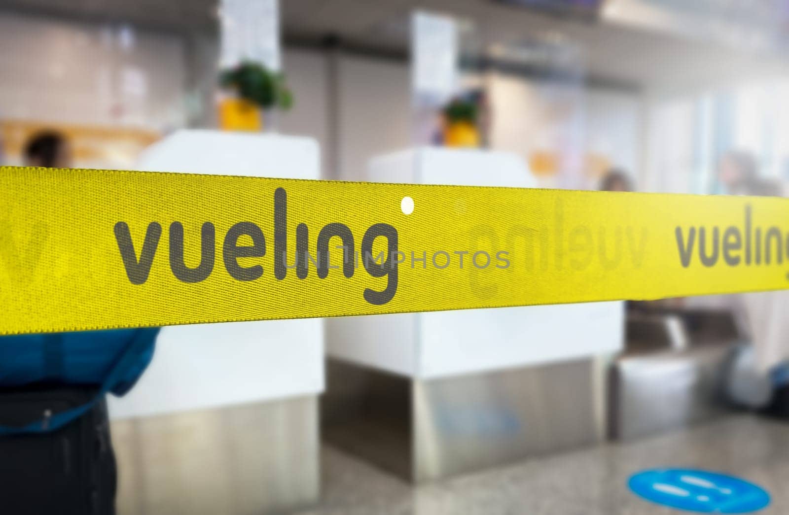 Madrid, SP, June 21 2023: Yellow retractable belt barrier with grey Vueling airlines logo. Spanish low-cost airline operating primarily in Europe. Travel and airport security. Illustrative editorial