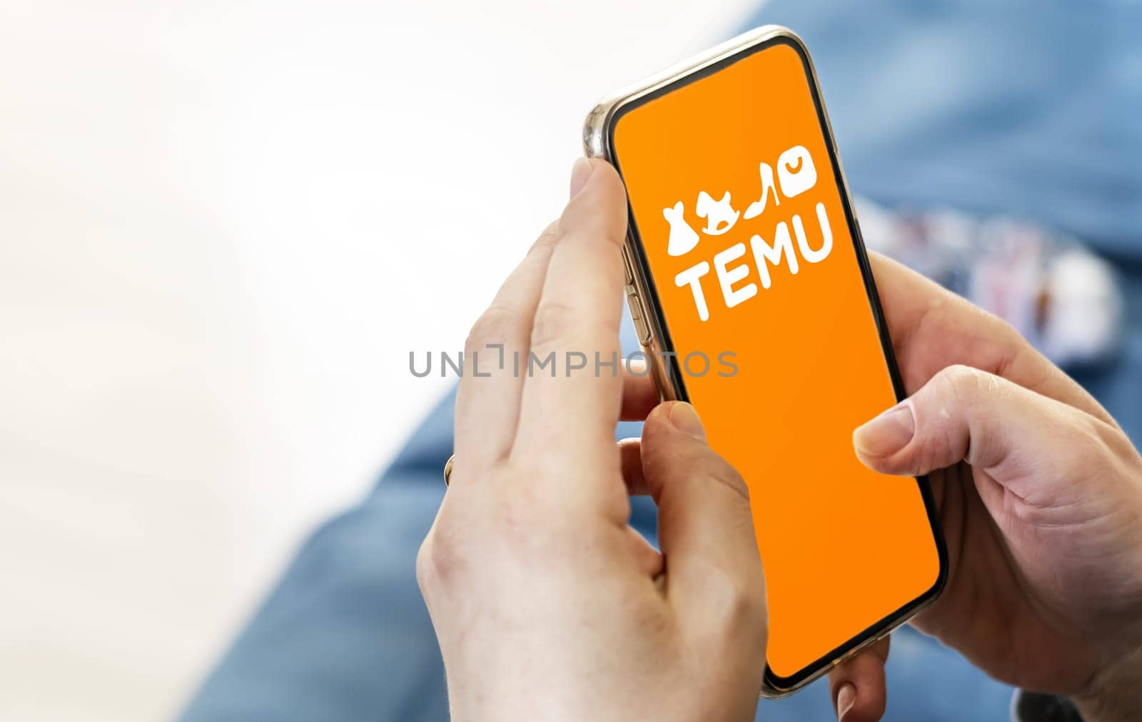 Boston, US, March 2023: Female hands holding a phone with Temu logo displayed on the screen. Temu is an online marketplace. Illustrative editorial