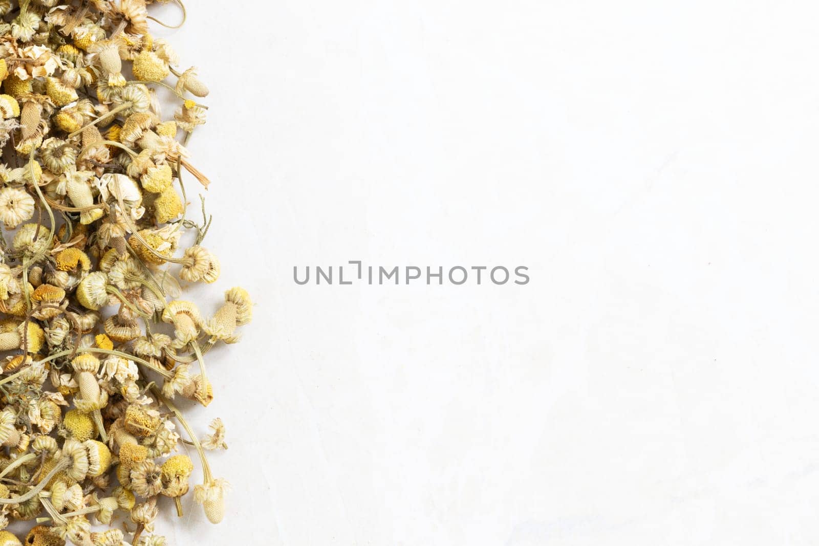 Dried chamomile flowers on marble surface with copy space.