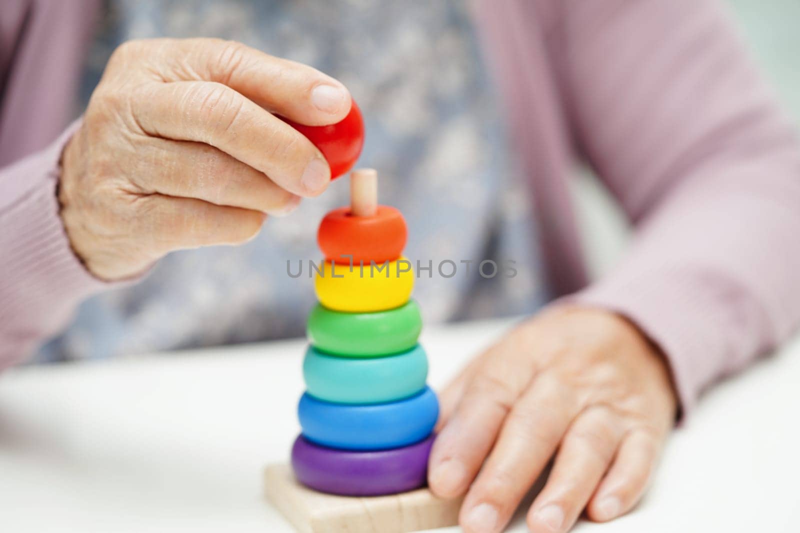 Asian elderly woman playing puzzles game to practice brain training for dementia prevention, Alzheimer disease.