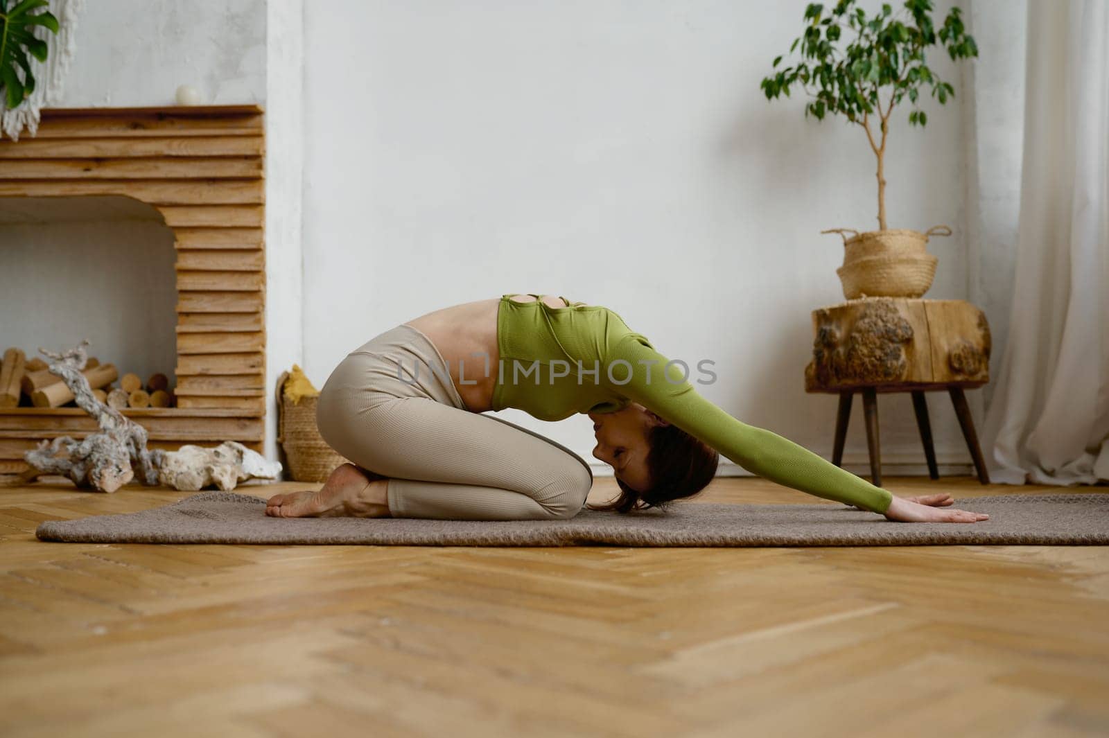 Young woman doing yoga stretching exercise on the floor. Wellbeing and healthy sport lifestyle concept