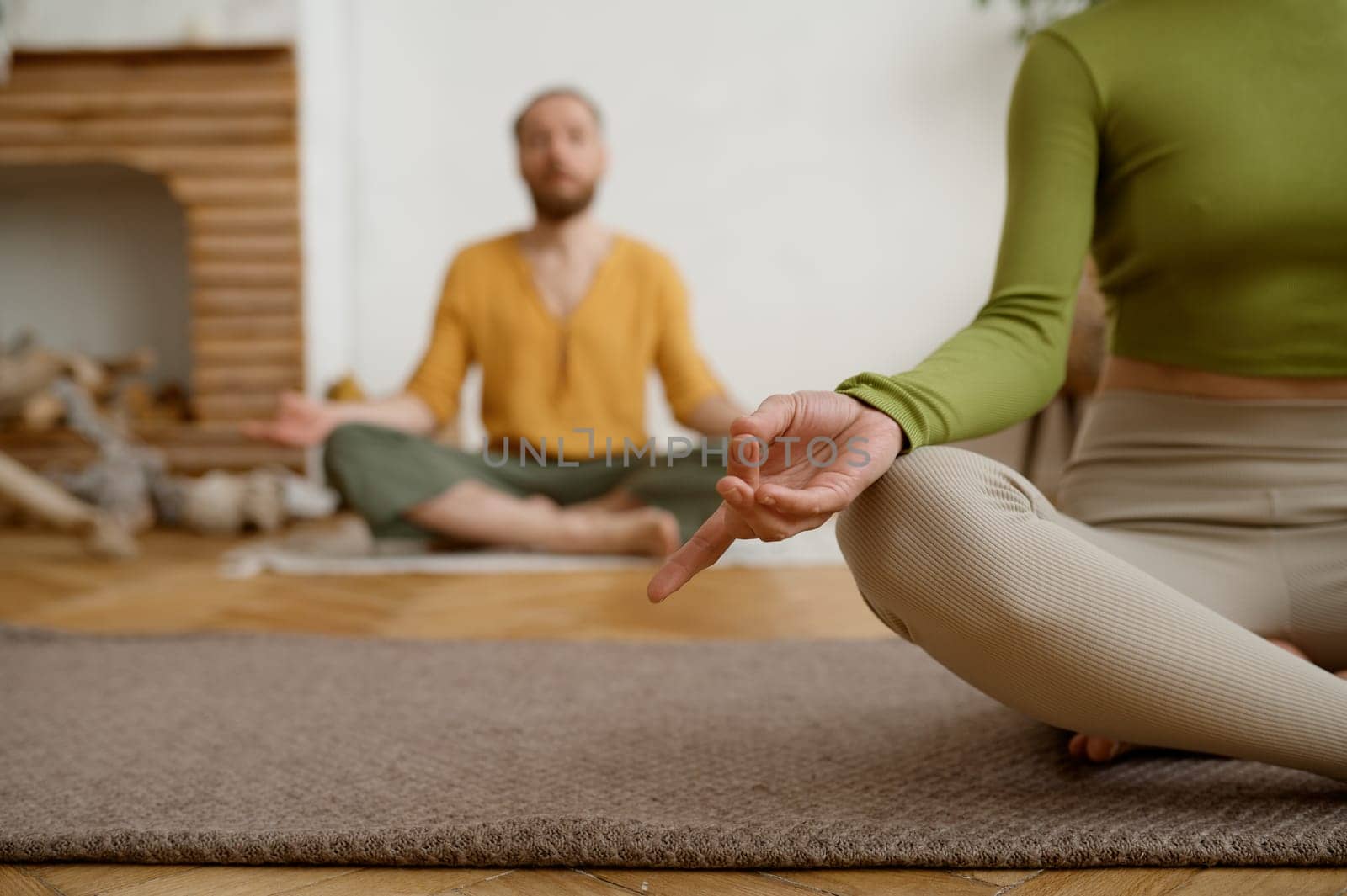 Young couple practicing meditation sitting in lotus position. Morning yoga in pair, mindfulness exercise for wellness and relaxation