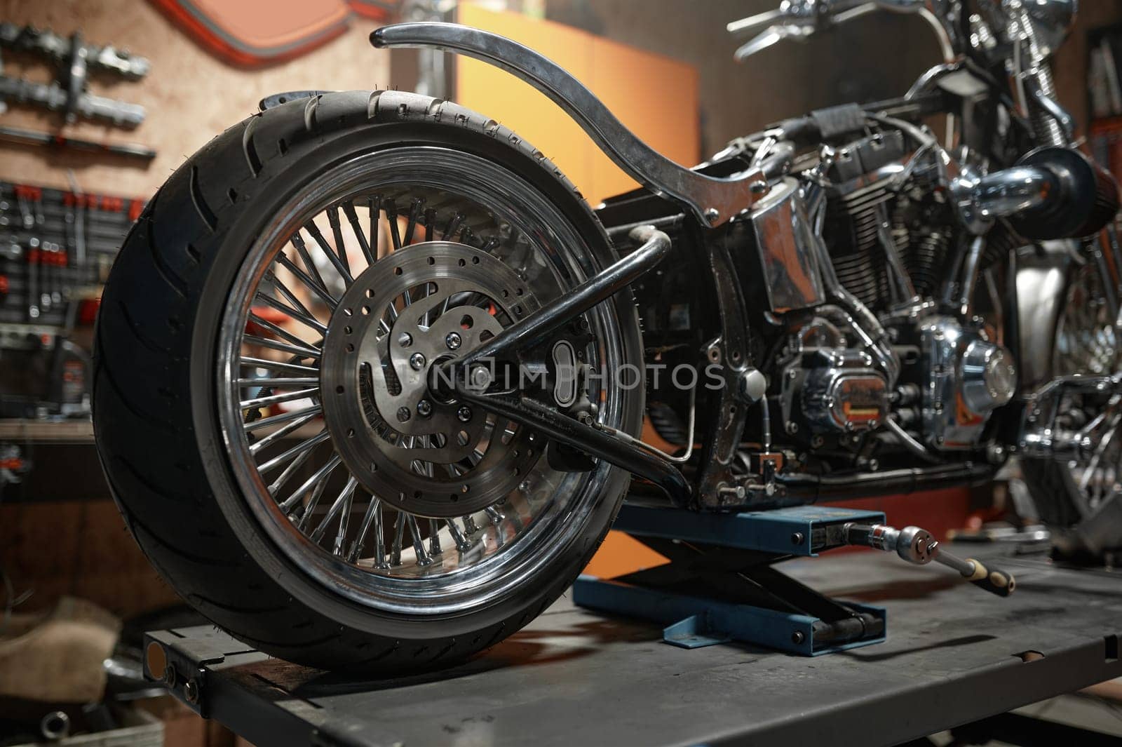 Closeup side view of custom motorcycle placed on lift platform at service station. Sport motorbike maintenance in garage