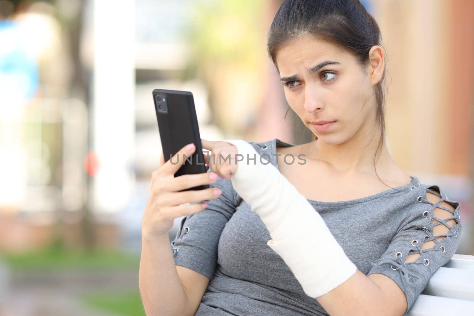 Suspicious convalescent girl checking phone content in the street