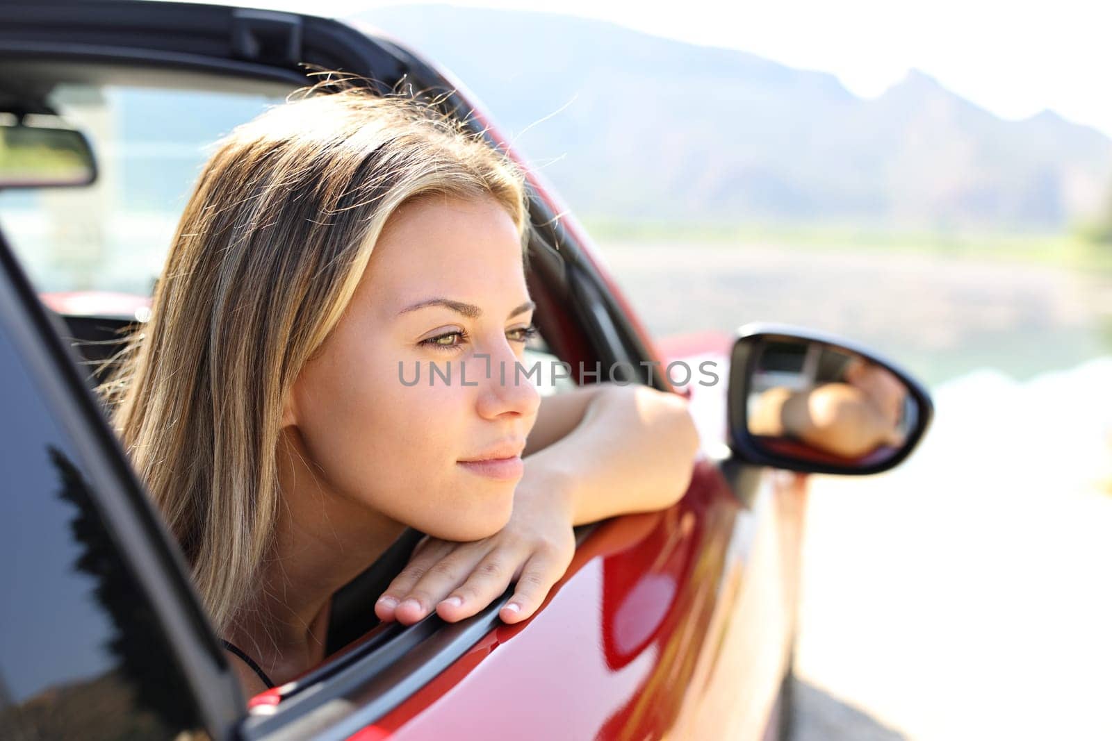 Beautiful car driver looking away in nature