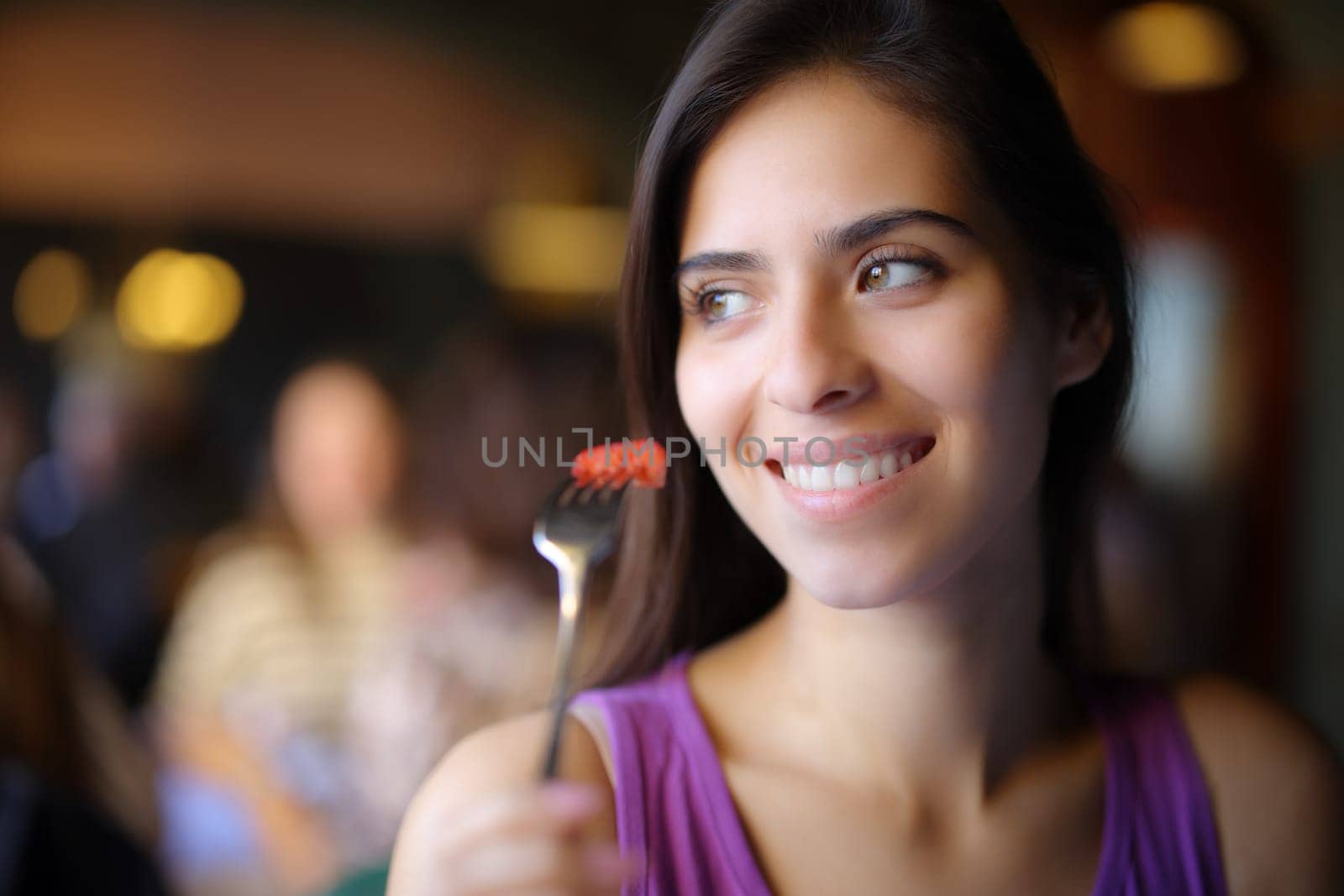 Happy woman eating strawberry and looking at side in a restaurant