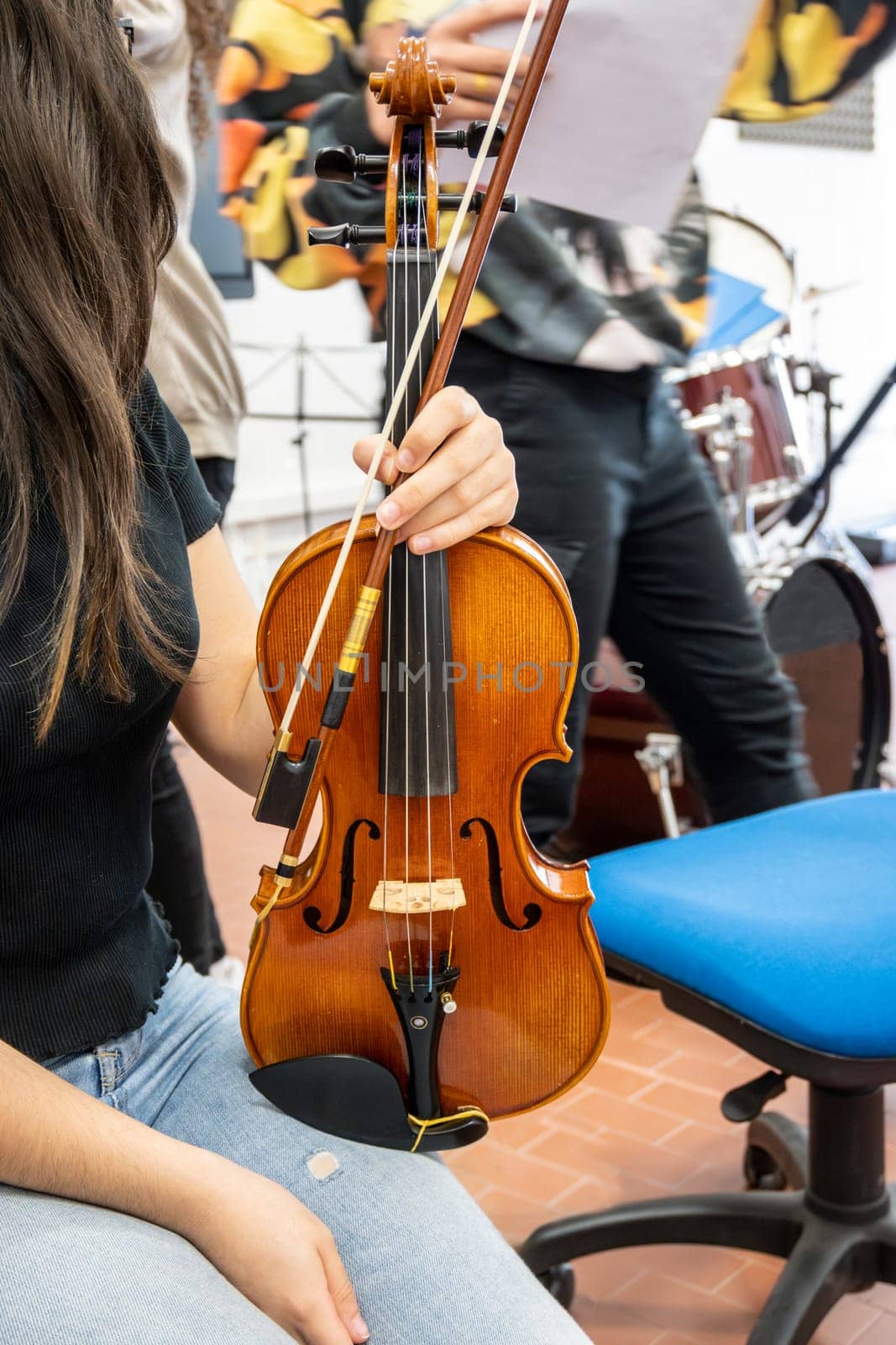 Real life young music students during rehearsals. Musical instruments and music stand with stave. Violin, drums, viola, flute