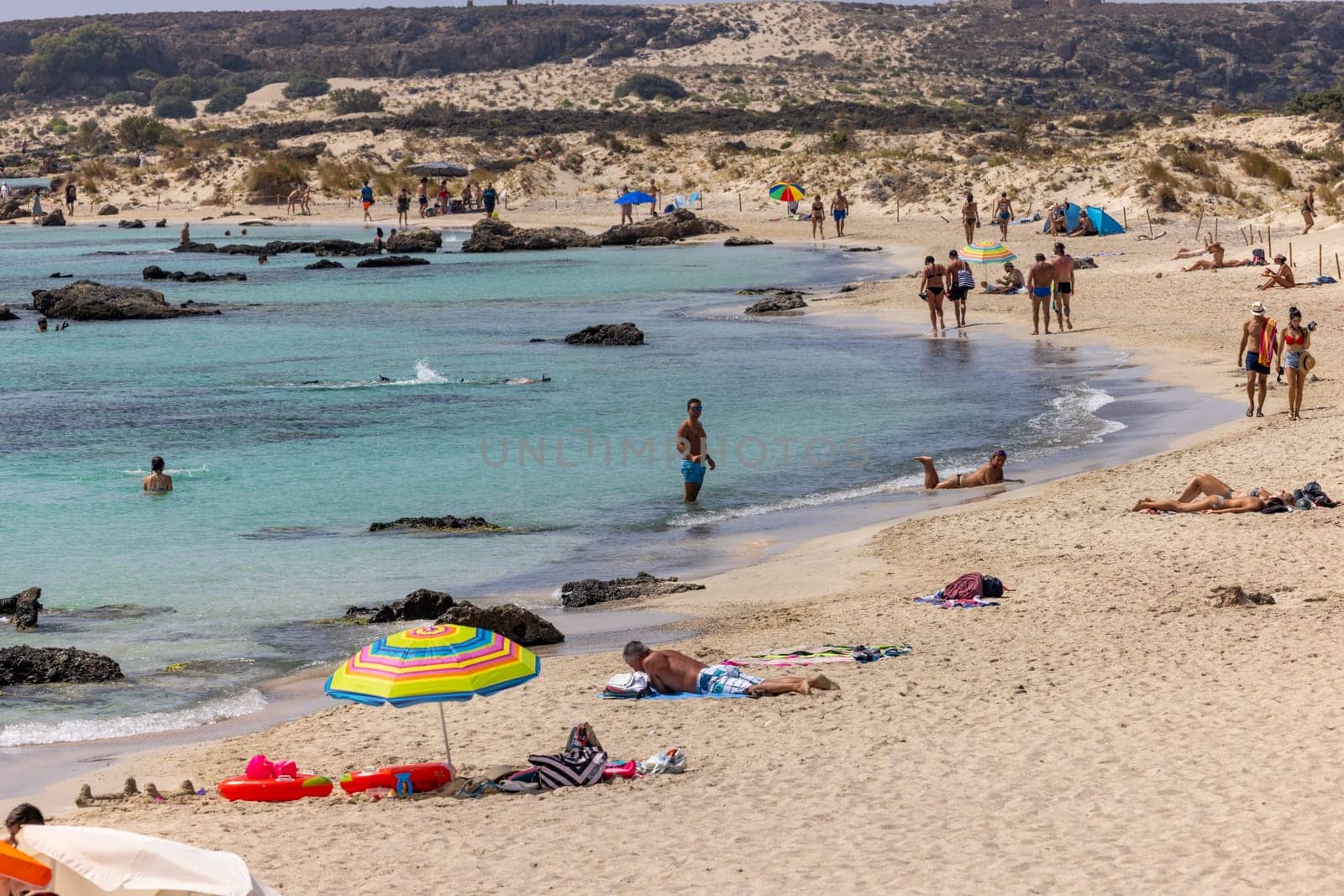 Elafonisi, Crete, Greece - Sept 19, 2021: People relaxing on the famous pink coral beach of Elafonisi on Crete, Mediterannean sea, Greece