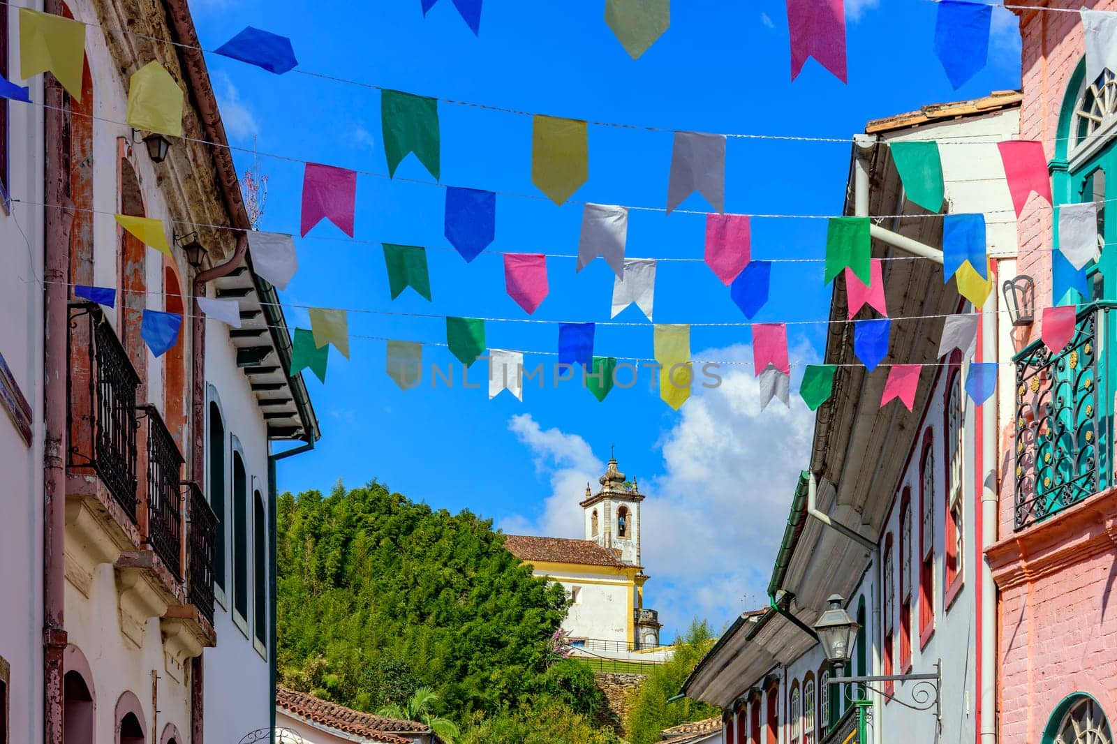 Street decorated with flags for the Saint John festivities with colonial-style houses and a church in the background in the city of Ouro Preto
