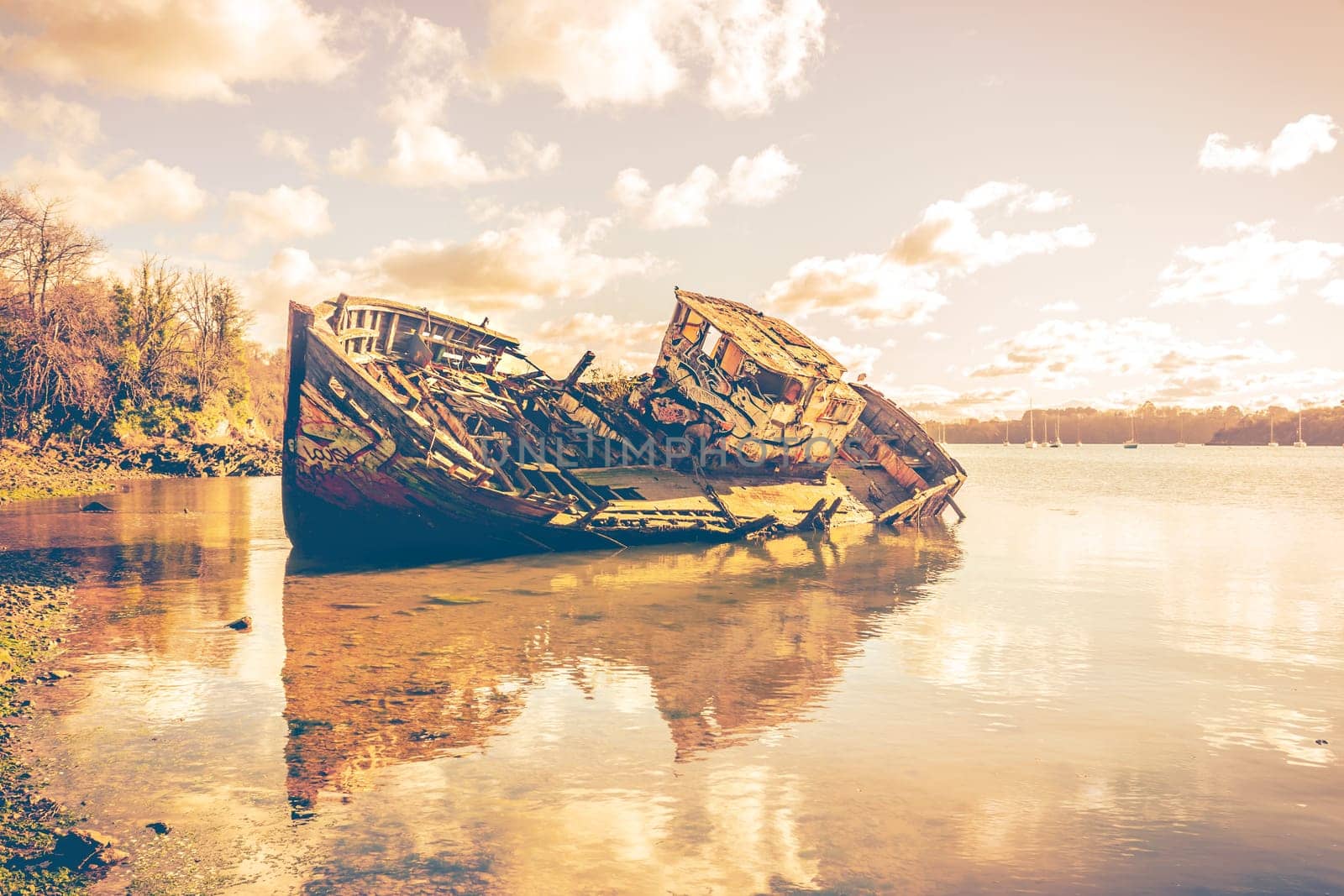 Wreck of a wooden fishing boat abandonedon the shore, Quelmer near Saint-Malo, France. Real photography