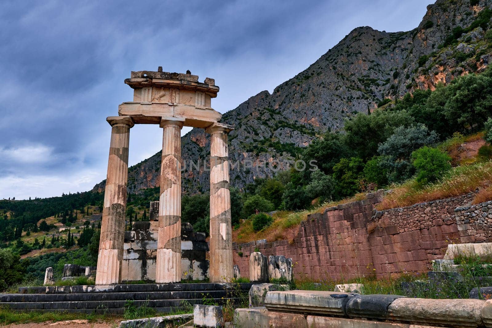 Ruins of Tholos of ancient Greek goddess Athena Pronaia in Delphi, Greece. Three Doric columns with relieves on frieze of circular temple on slope of sacred mount Parnassos and next to famous Delphi complex. UNESCO World heritage site. Close view