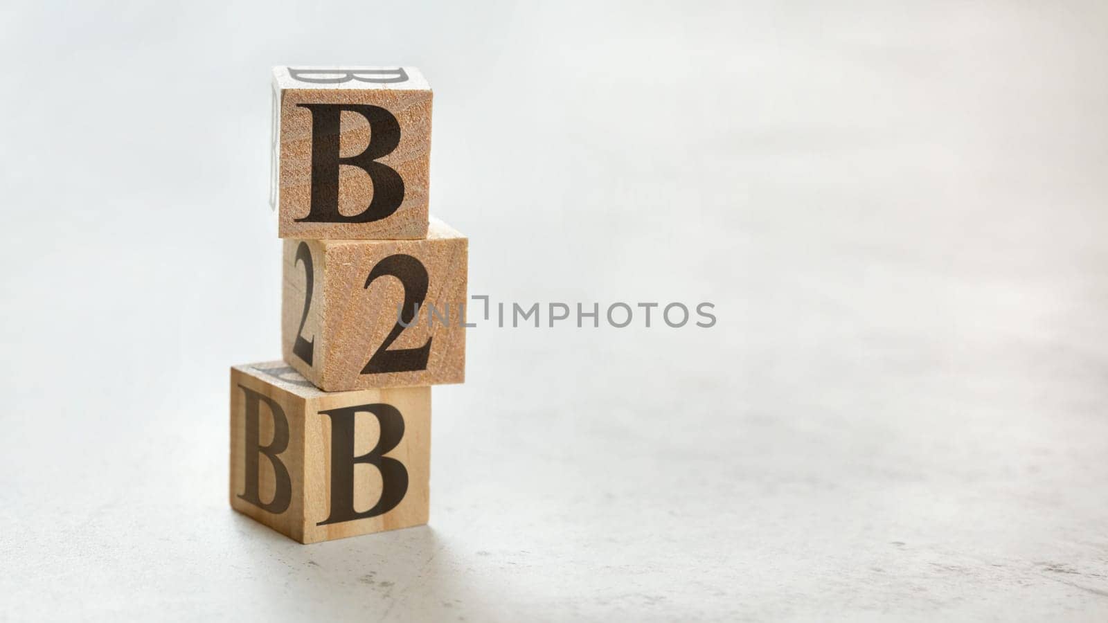 Pile with three wooden cubes - letters B2B meaning Business to Business on them, space for more text / images at right side.
